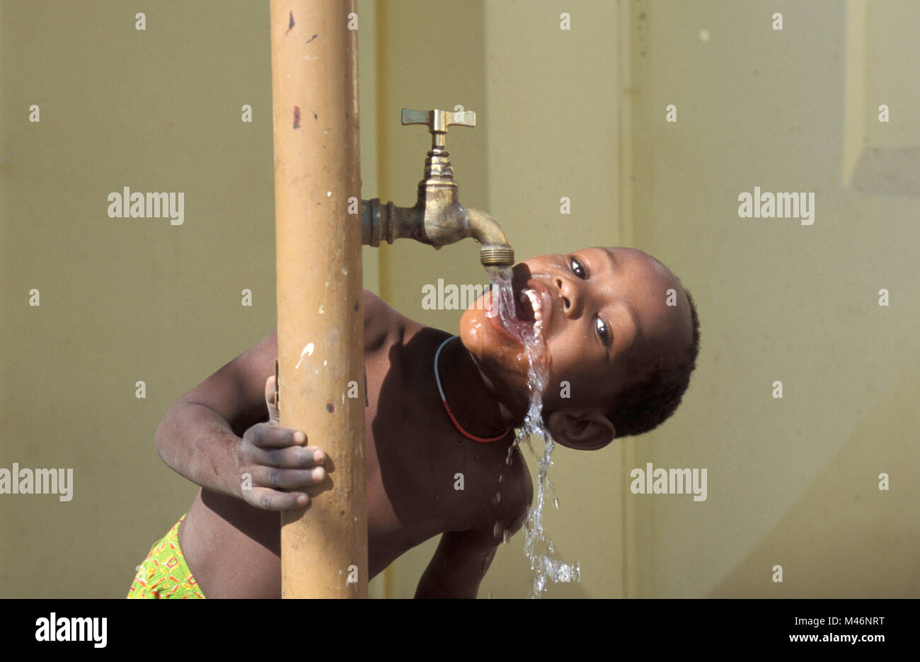 Namibia Windhoek. Township: Goreangab. Ragazzo di bere acqua dal rubinetto. Foto Stock