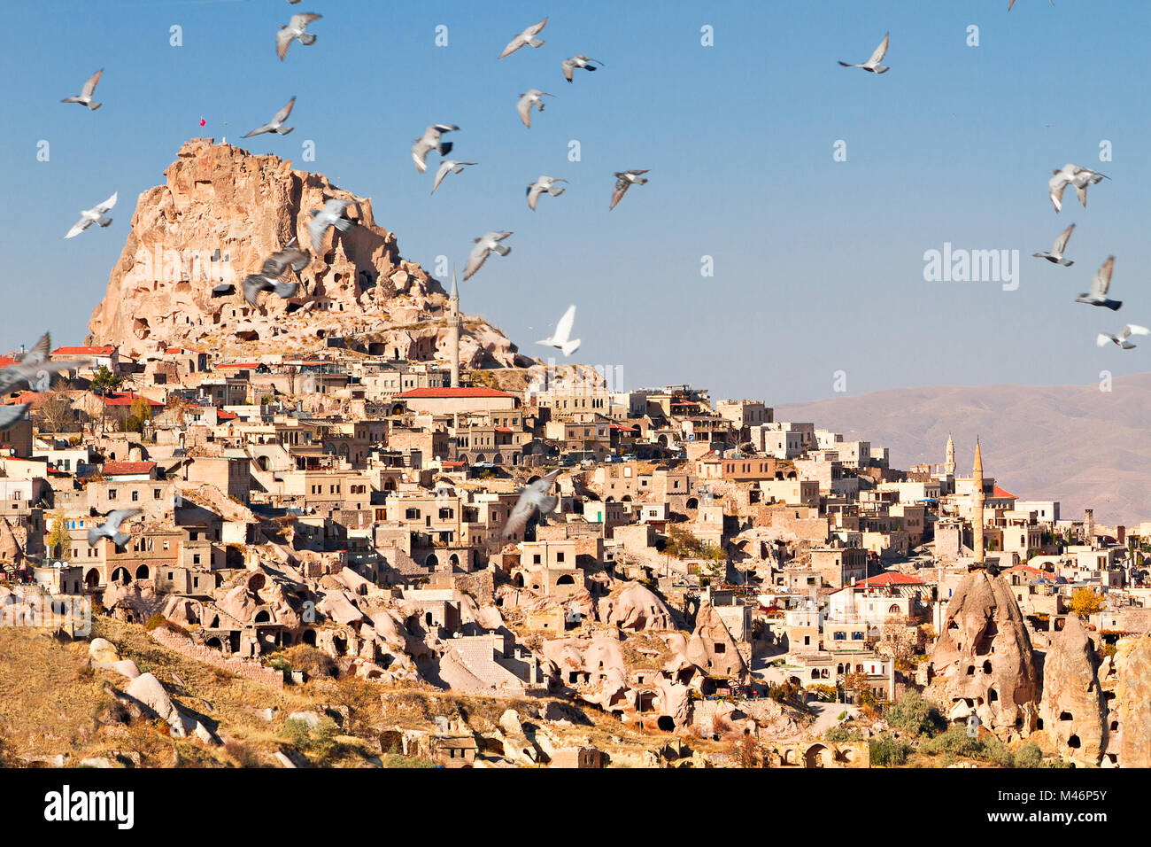 Il Castello di Uchisar in Cappadocia, Turchia con piccioni in volo da la Valle di piccione. Foto Stock