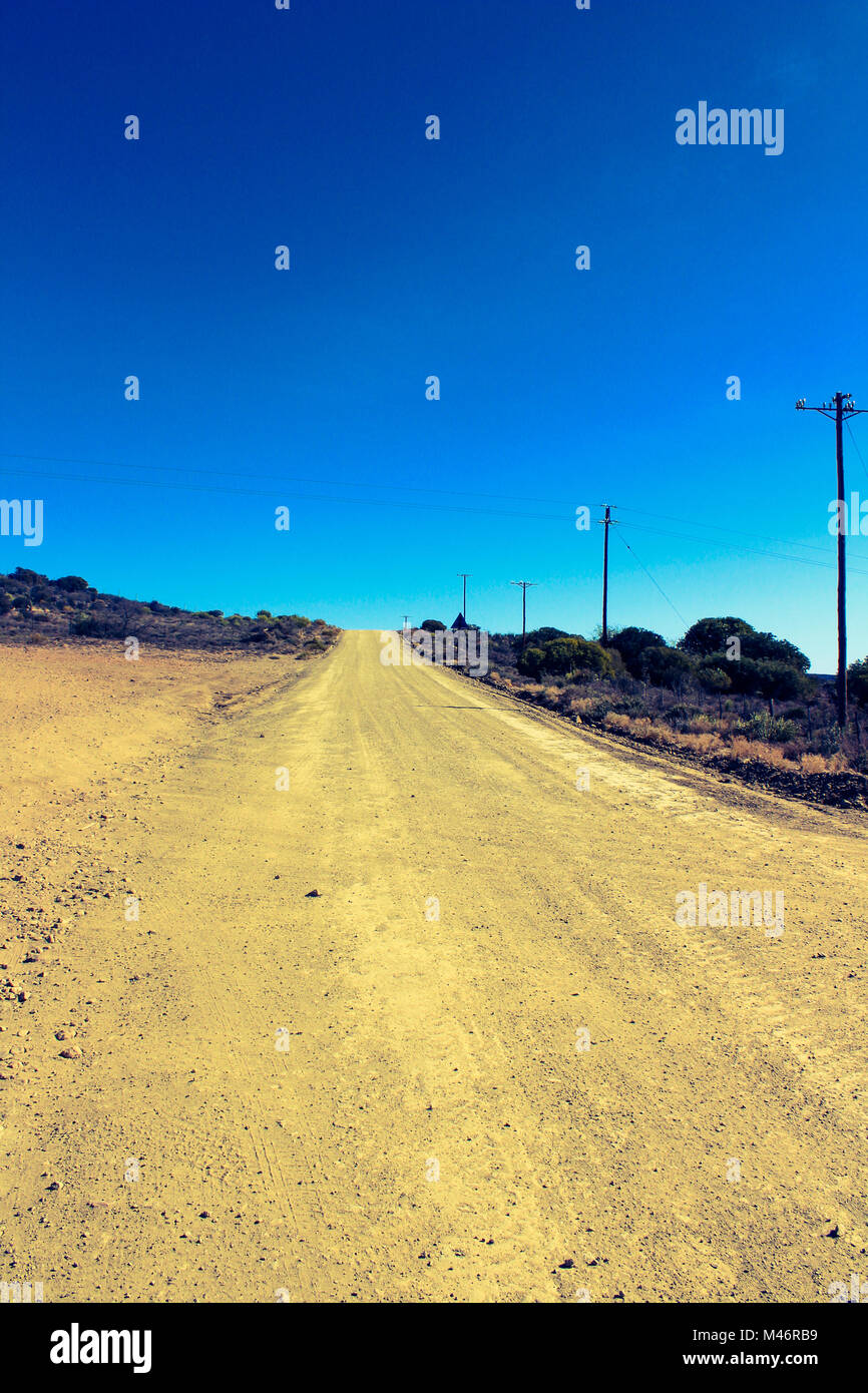 Il polveroso, vecchia fattoria strada che conduce attraverso la Warmwaterbergspa campeggio in Klein Karoo, Sud Africa Foto Stock