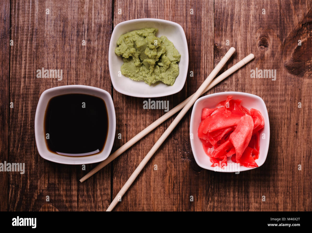 Bastoni, Wasabi, la salsa di soia e zenzero sott'aceto per sushi in legno marrone sfondo tabella. Vista dall'alto. Foto Stock