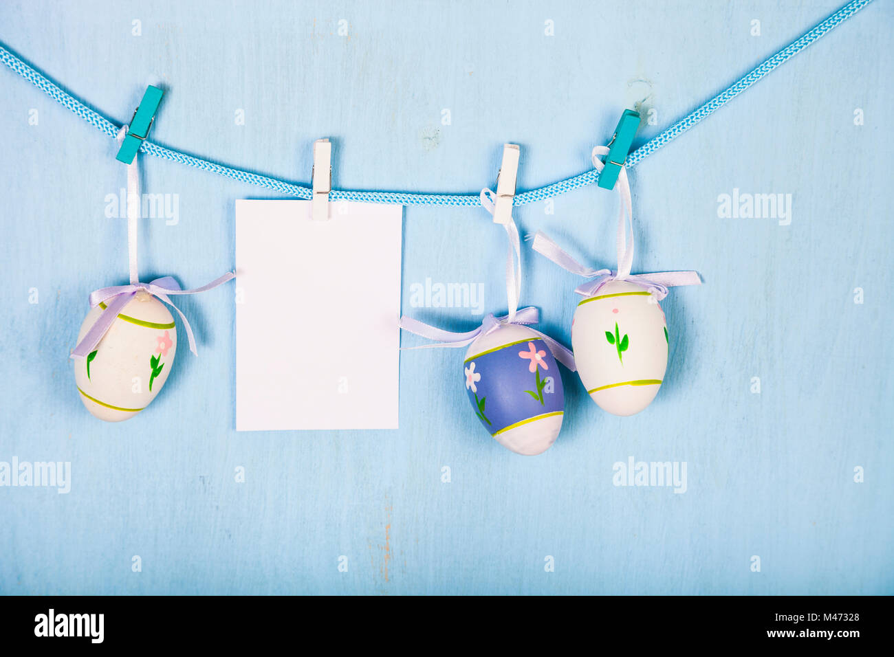 Uova di Pasqua e la carta su una fune su un blu sullo sfondo di legno. Pasqua ancora la vita può essere utilizzato come una cartolina. Foto Stock
