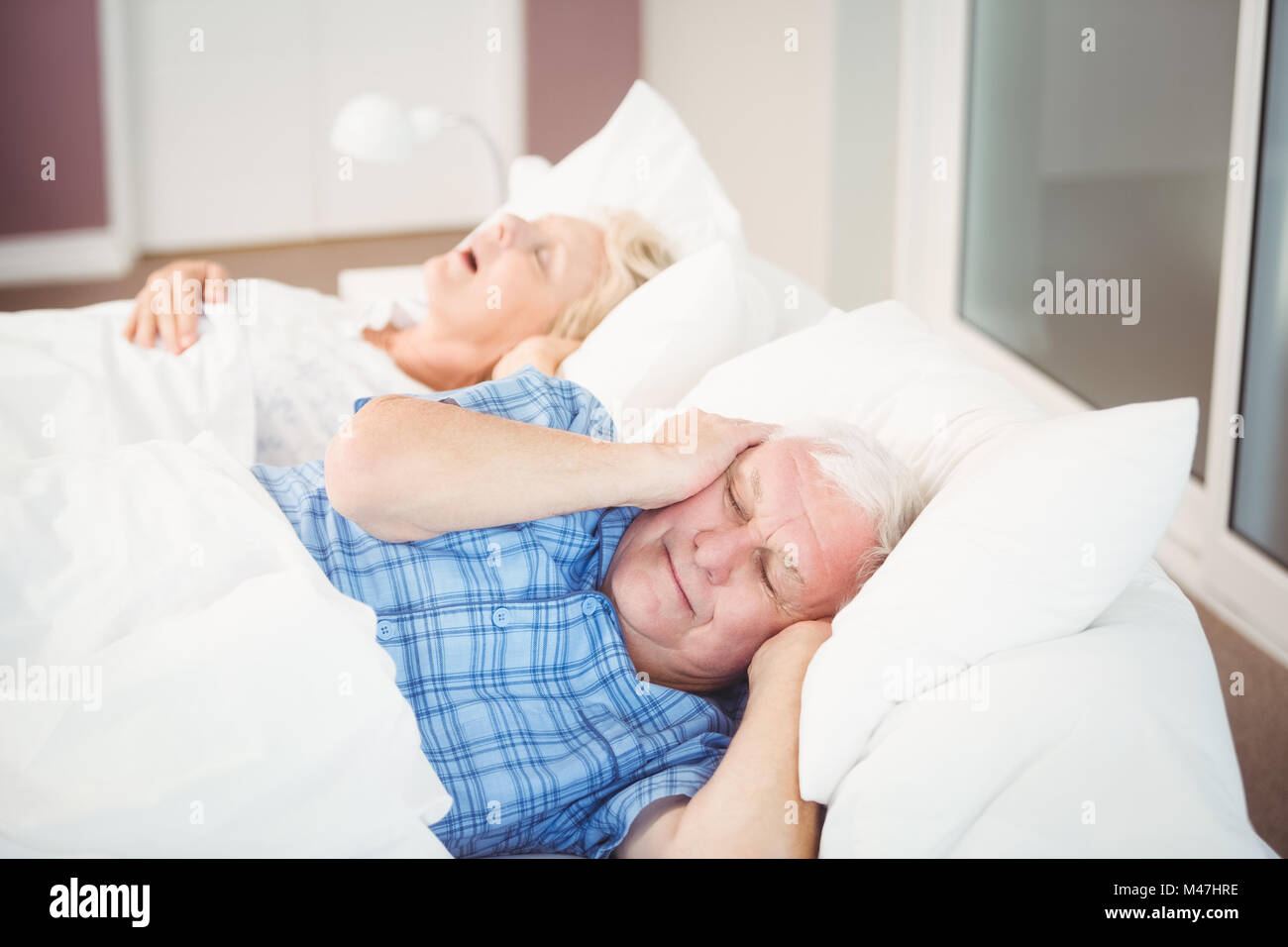 Disturbato l uomo che copre le orecchie dalla moglie per il russamento Foto Stock