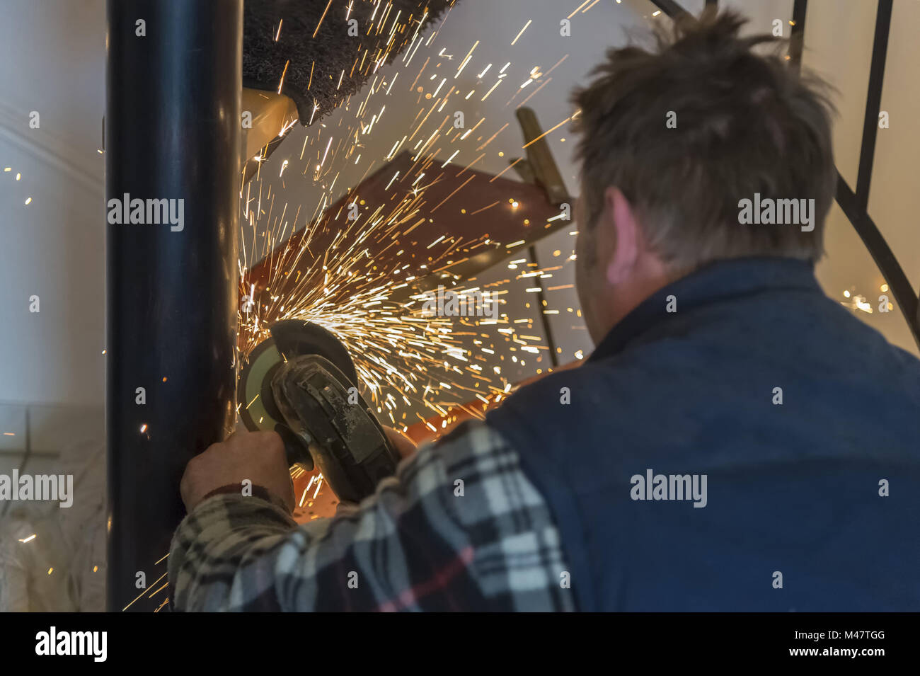 Un artigiano macina per una macchina di molatura da una saldatura. Foto Stock