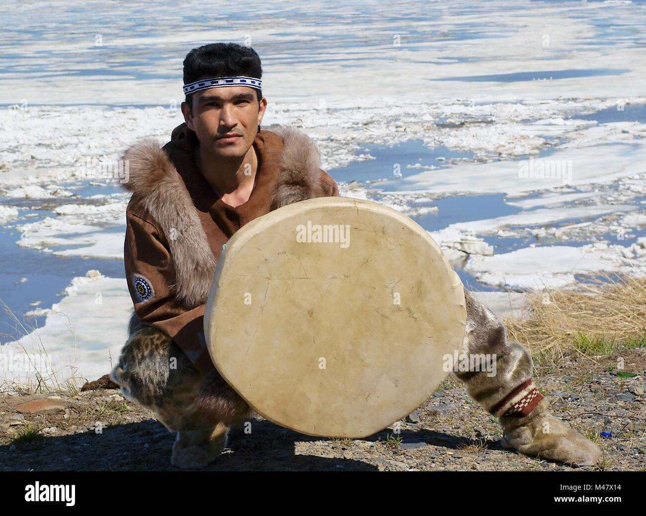 Chukchi uomo in abiti tradizionali è un ballo folk dance con il tamburello e la spinge contro la molla a Chukotka paesaggio Foto Stock