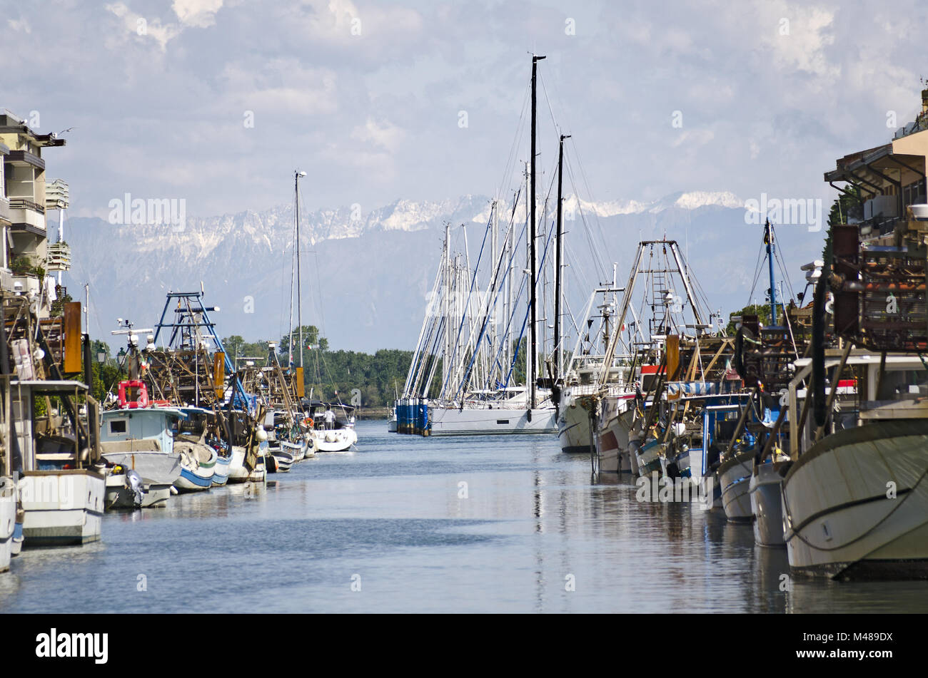 Montagne innevate alle spalle di barche da pesca e le navi a vela Foto Stock