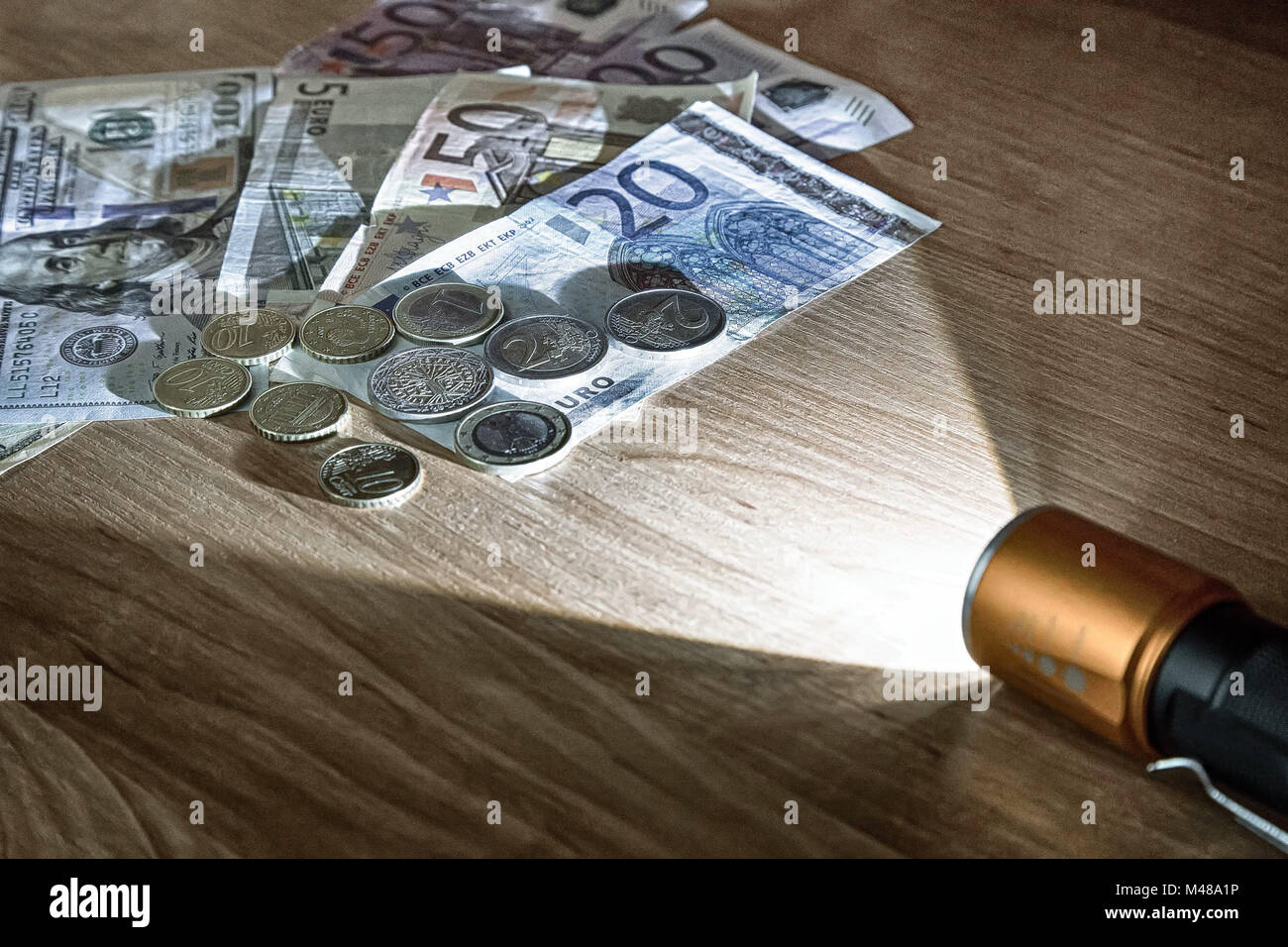 Denaro nel fascio di luce della torcia elettrica. Foto Stock
