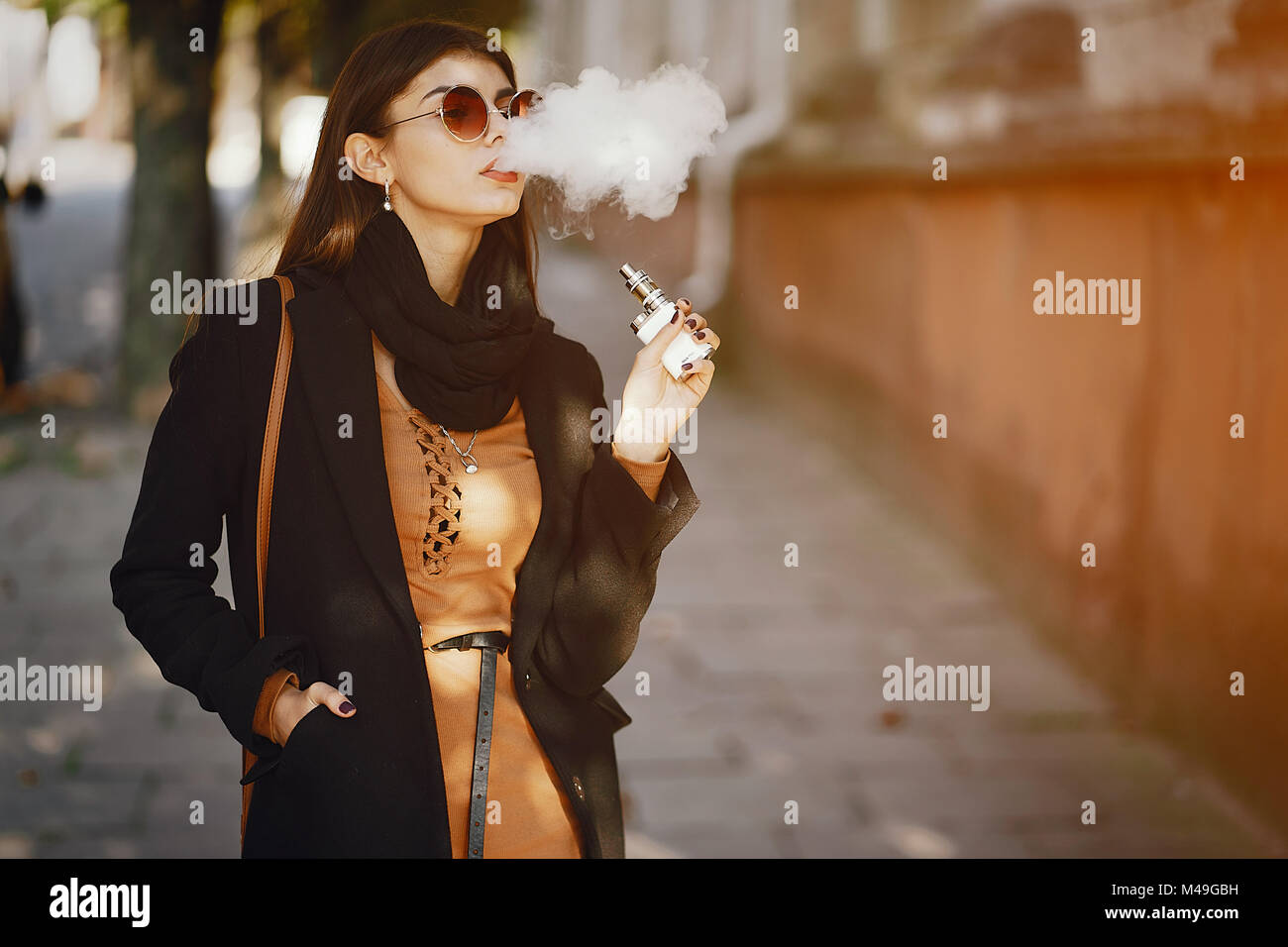 Elegante ragazza di fumare un e-sigaretta Foto Stock