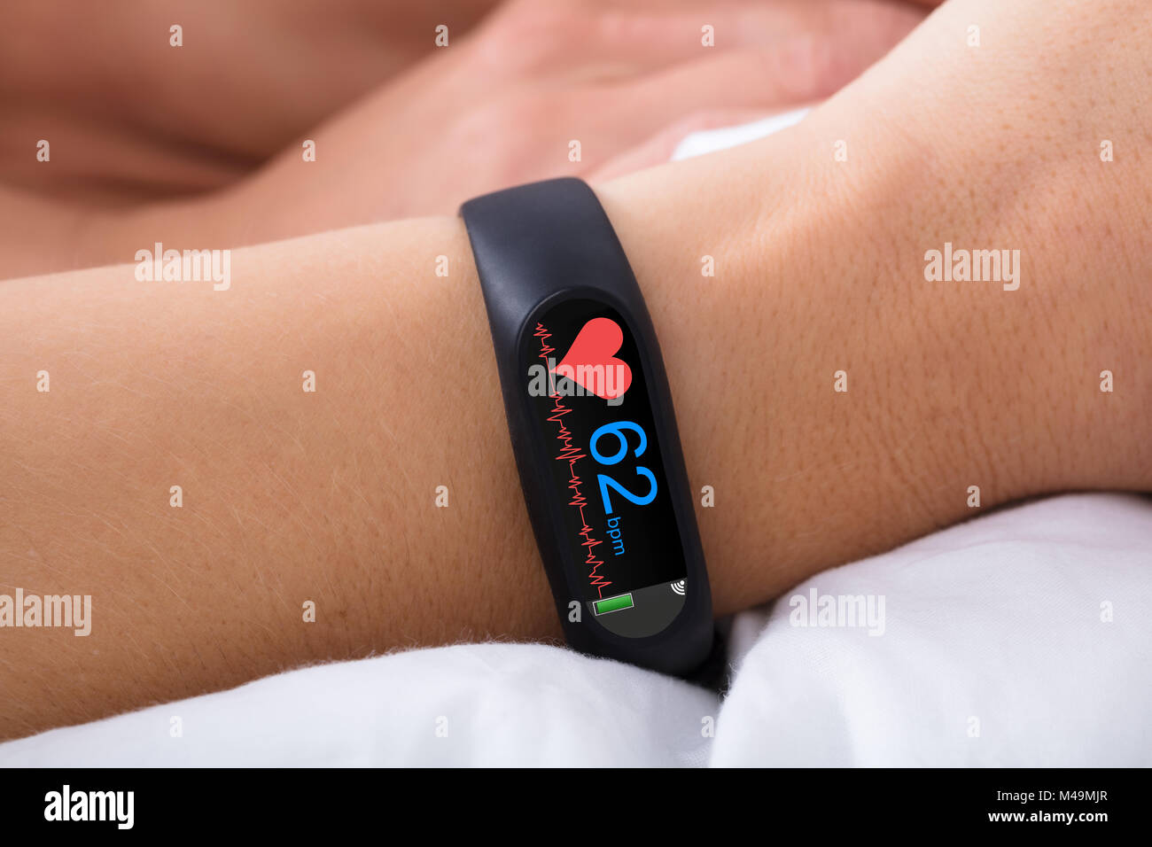 Close-up di attività Fitness Tracker con il battito cardiaco sulla donna di mano sul letto Foto Stock