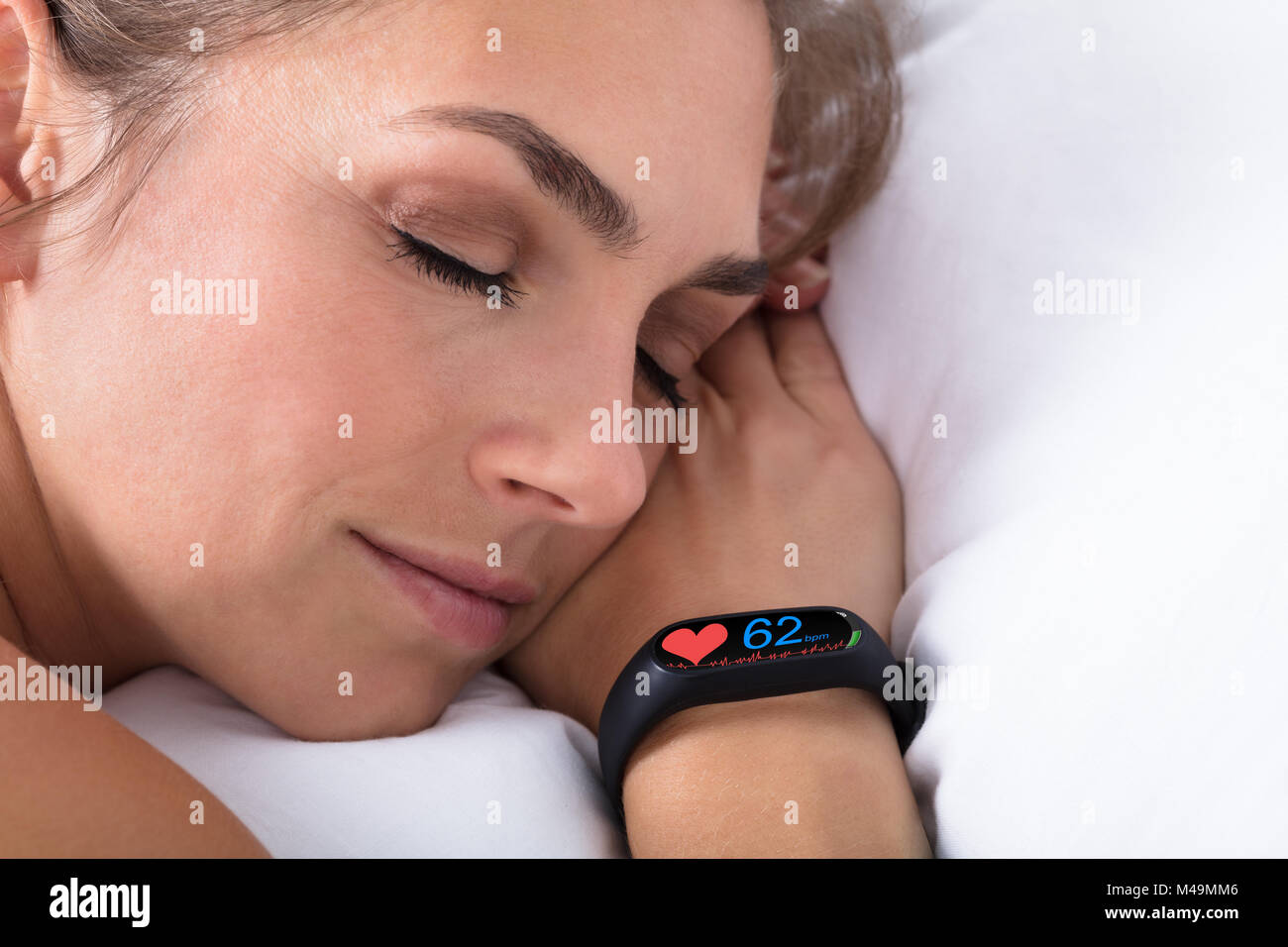 Attività Fitness Tracker con il battito cardiaco sulla donna mano sul letto Foto Stock