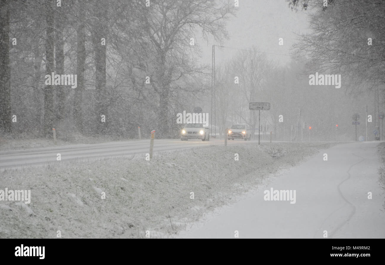 Il traffico di tipo sparse muovendo lentamente, su una strada durante la nevicata che causa una ridotta visibilità. Foto Stock