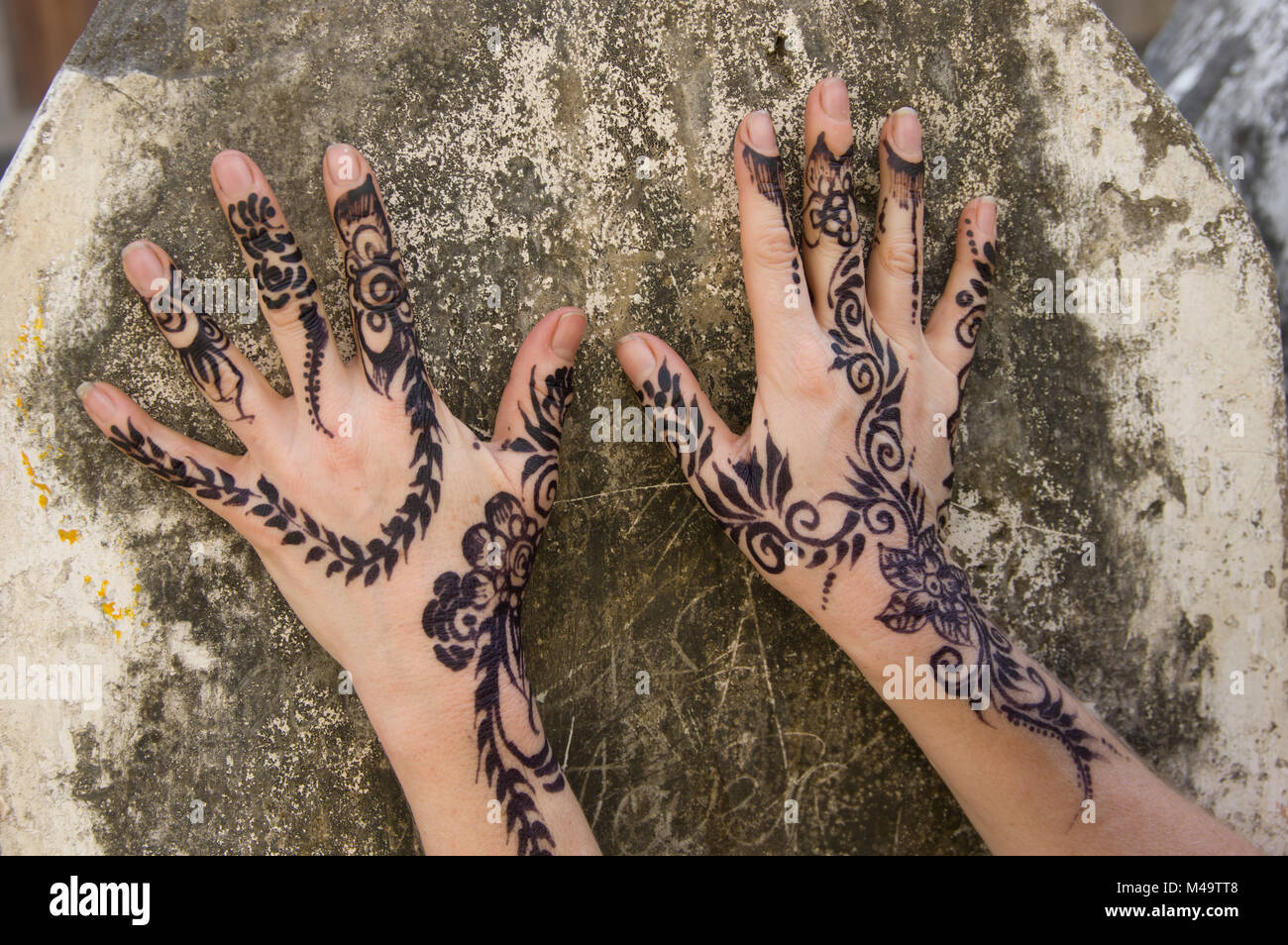 Donna di henna decorate le mani contro un muro di pietra nella città di pietra, Zanzibar, Tanzania in una luminosa e soleggiata giornata Foto Stock