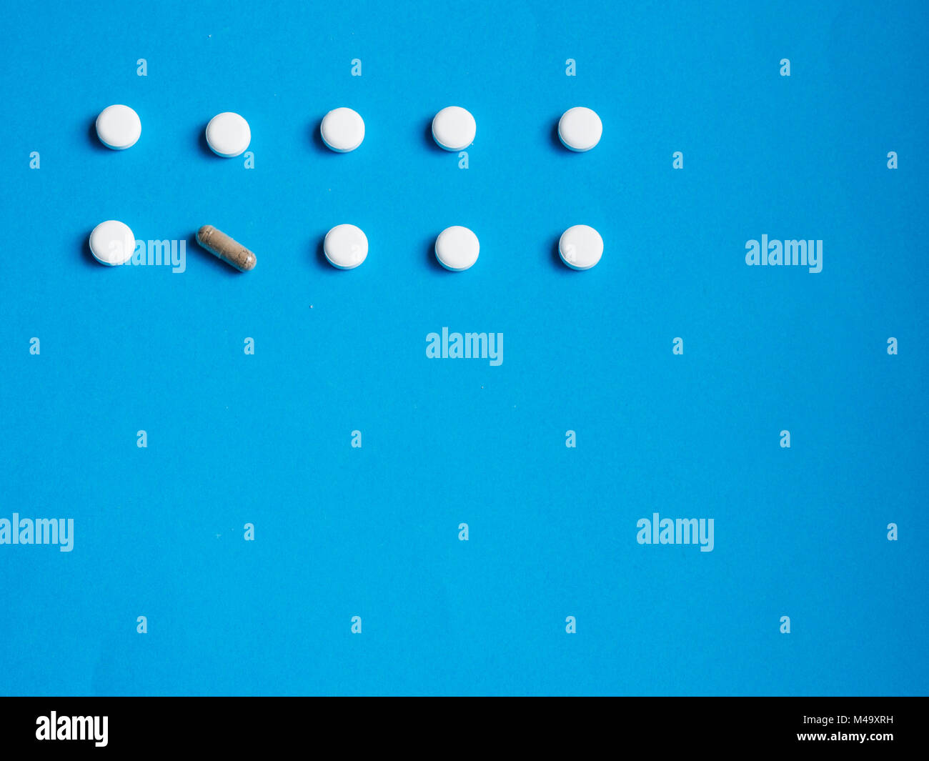 Pillole di bianco e una capsula su sfondo blu (medicina alternativa concetto) Foto Stock