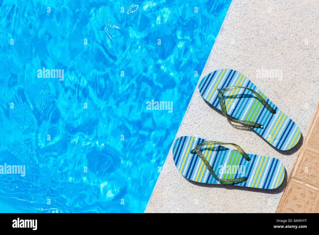 Due pantofole di balneazione sul bordo della piscina Foto Stock