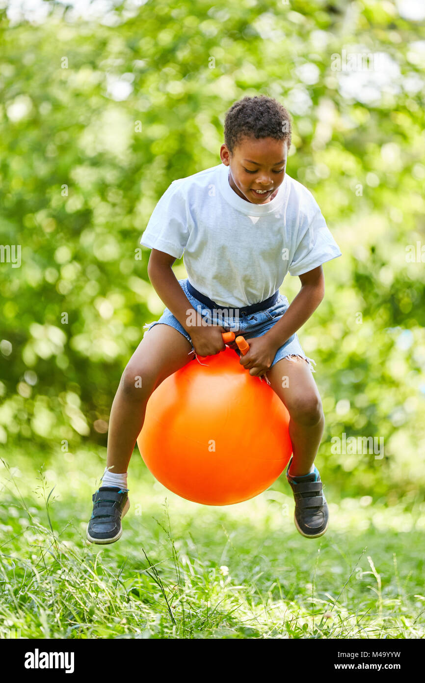 Ragazzo africano è saltando su una sfera di salto in estate nel parco Foto Stock