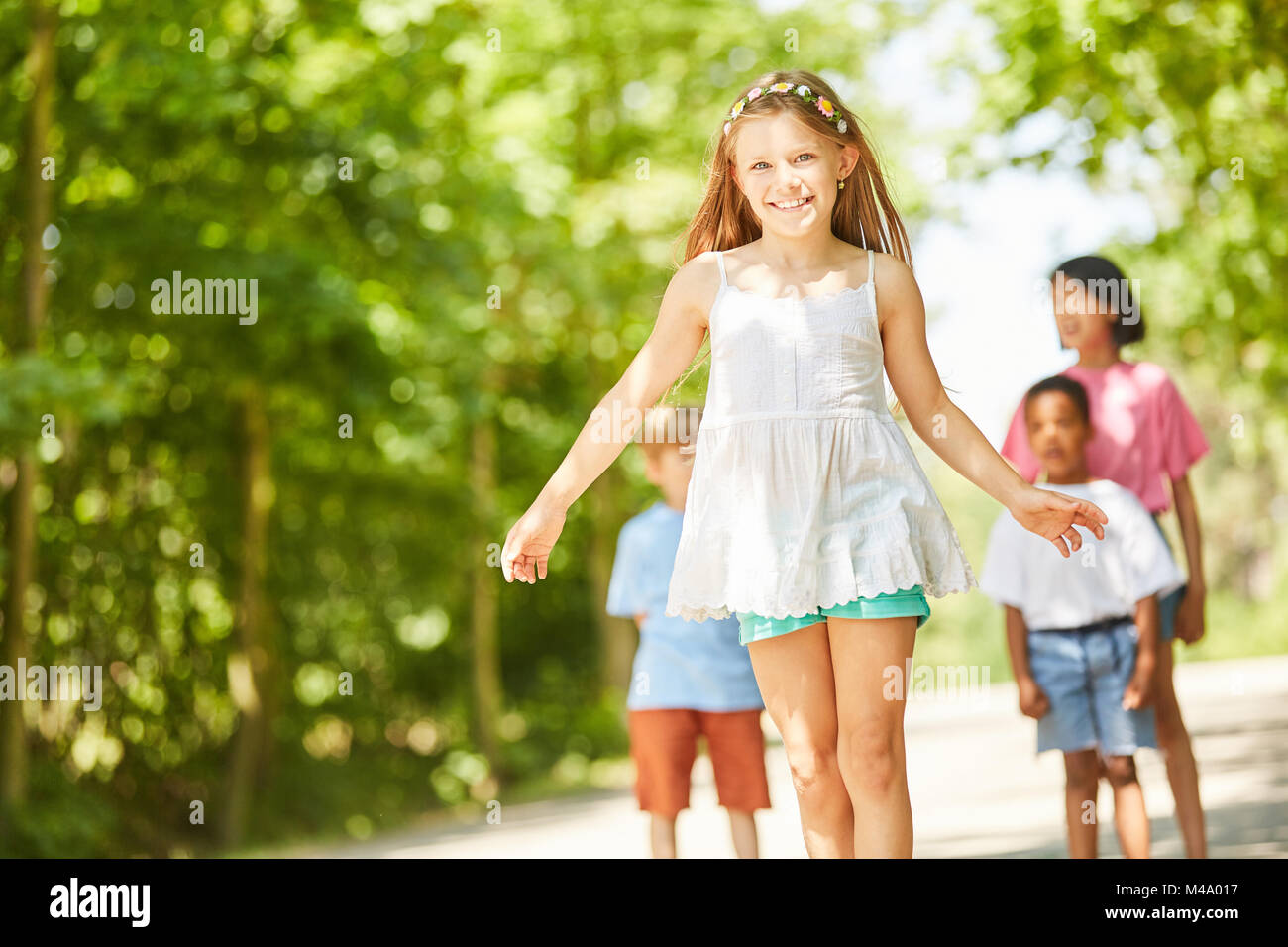 Sorridente ragazza impara a skateboard in estate con gli amici Foto Stock