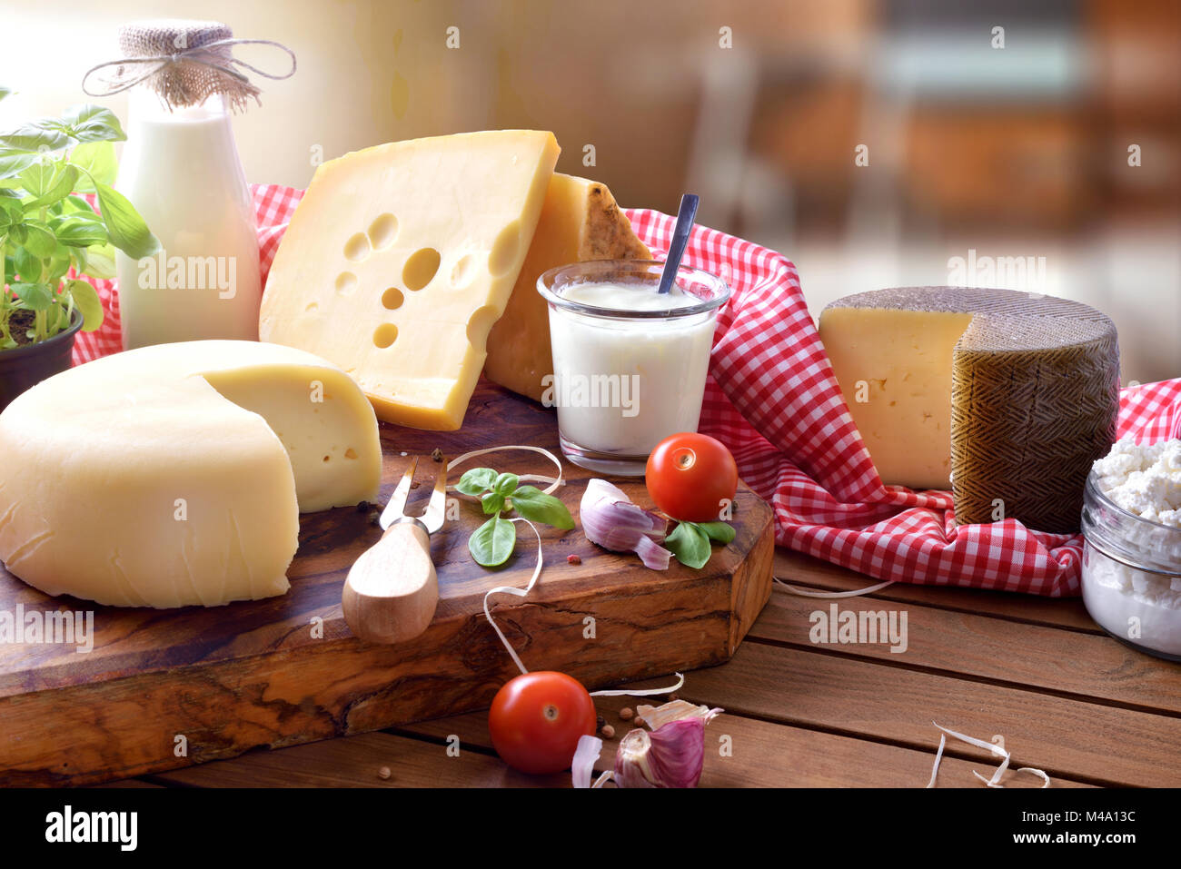 Assortimento di caseificio artigianale prodotti su di un tavolo di legno in cucina rustica. Vista in elevazione. Composizione orizzontale Foto Stock