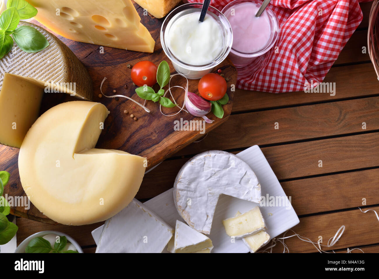 Assortimento di caseificio artigianale prodotti su di un tavolo di legno in cucina rustica. Vista dall'alto. Composizione orizzontale Foto Stock