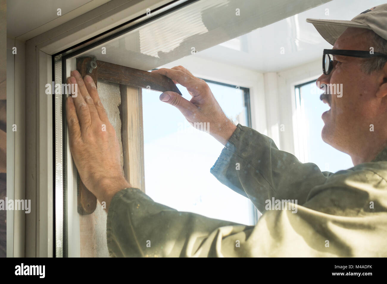 Carpentiere realizza misurazioni quando si installa la finestra Foto Stock