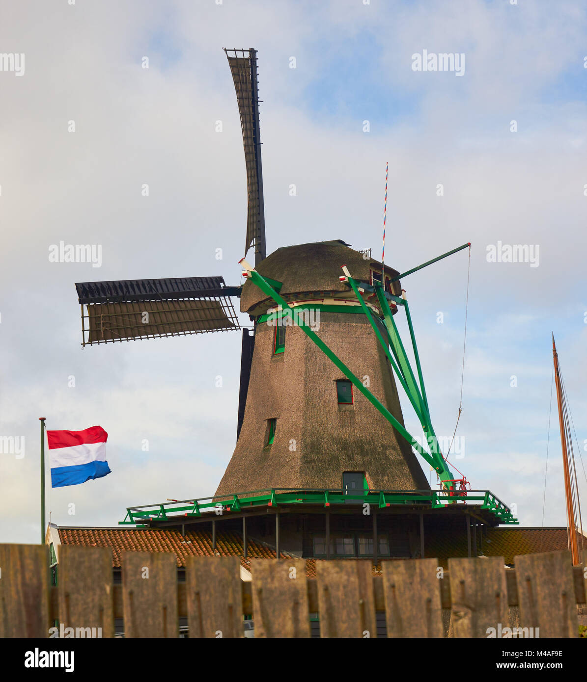 Bandiera olandese volare al di fuori di un mulino a vento, Zaanse Schans un villaggio nei pressi di Zaandijk nel comune di Zaanstad, North Holland, Paesi Bassi. Foto Stock