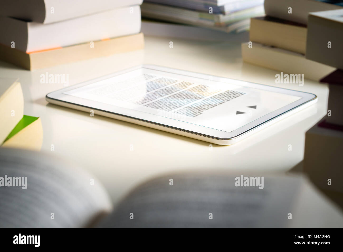 Lettore del libro elettronico. Moderne smart device per la lettura circondati da pile di libri tradizionali. Libreria o a casa. Foto Stock