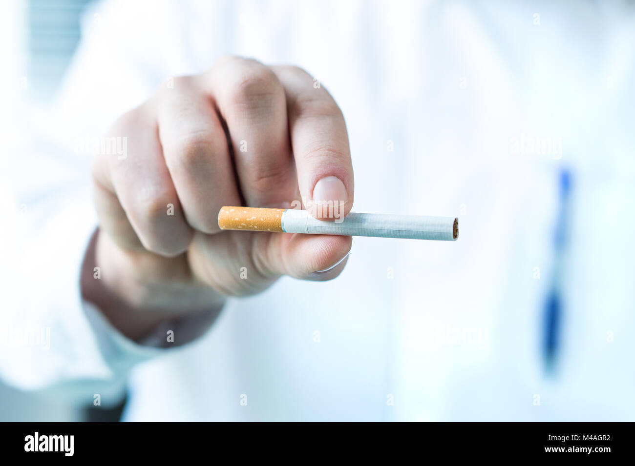 Medico tenendo una sigaretta tra le dita. Smettere di fumare concetto. Foto Stock