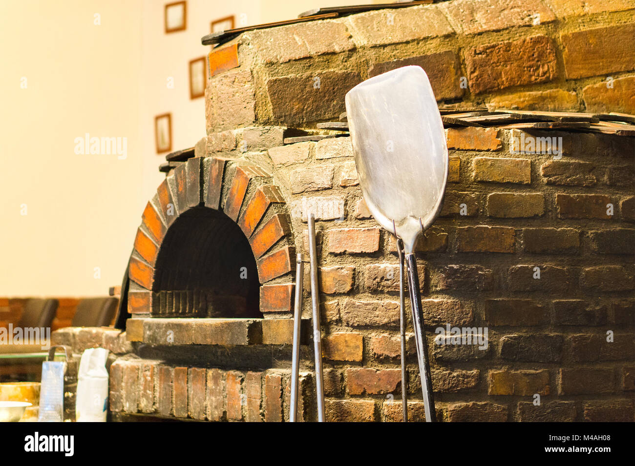 Mattone tradizionale forno. Pala Pizza appoggiata contro la pietra in una vecchia cucina. Foto Stock