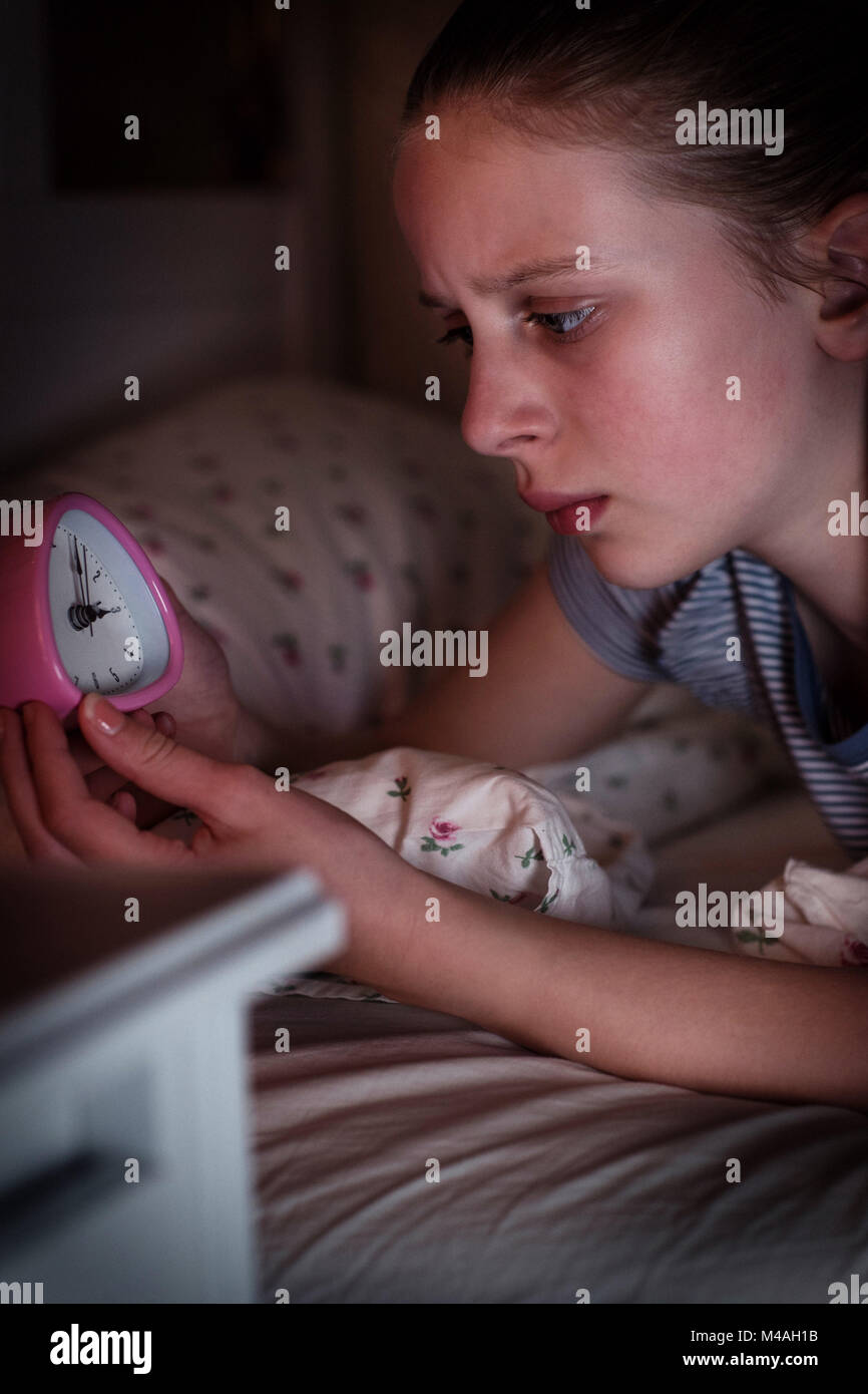 Ansiosi ragazza non riesce a dormire di notte guardando orologio Foto Stock