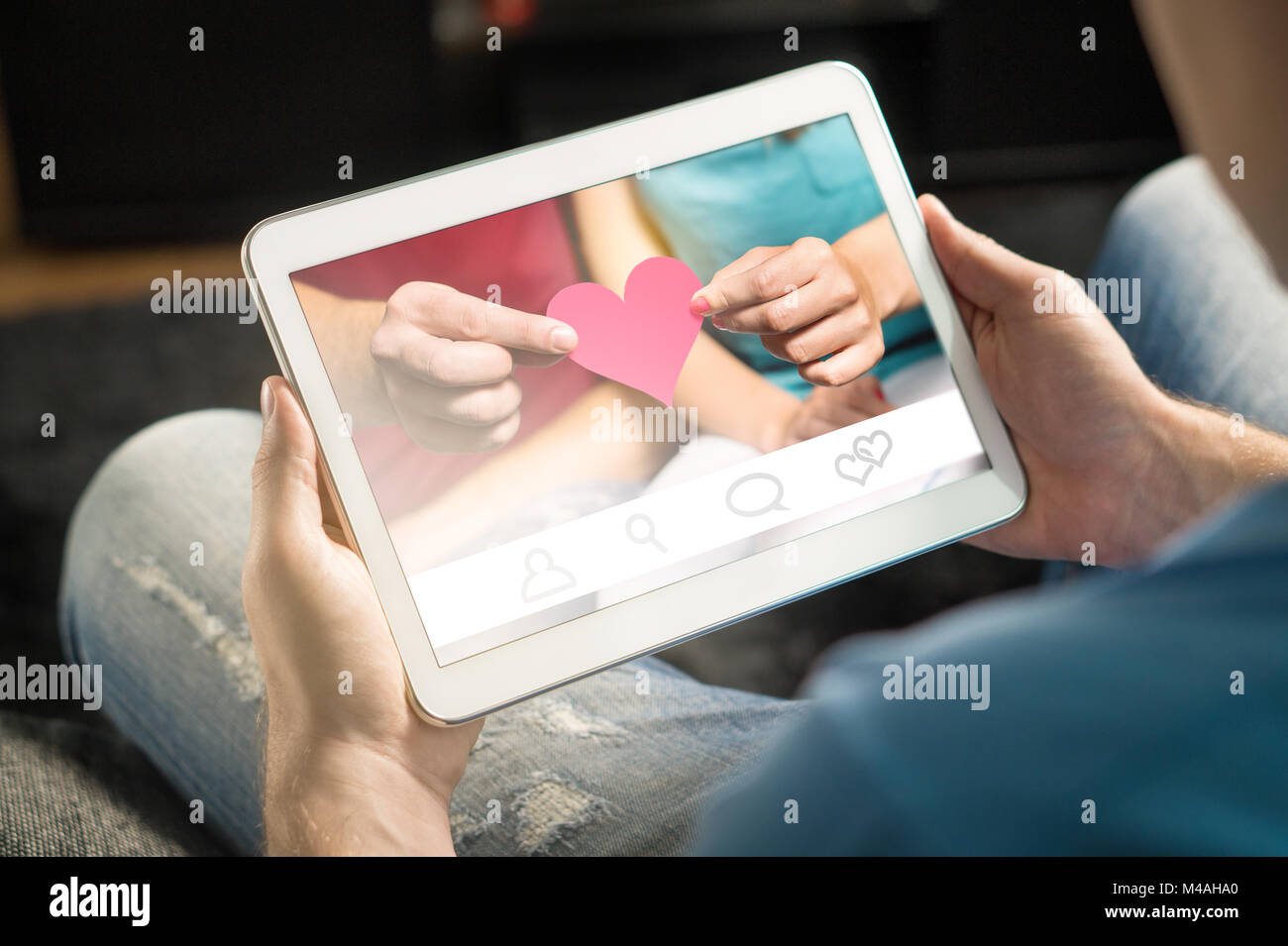 Online dating concetto. Imaginary applicazione o sito web. Trovare l'amore da internet utilizzando l'app. Uomo che utilizza e azienda tablet e smart device a casa. Foto Stock