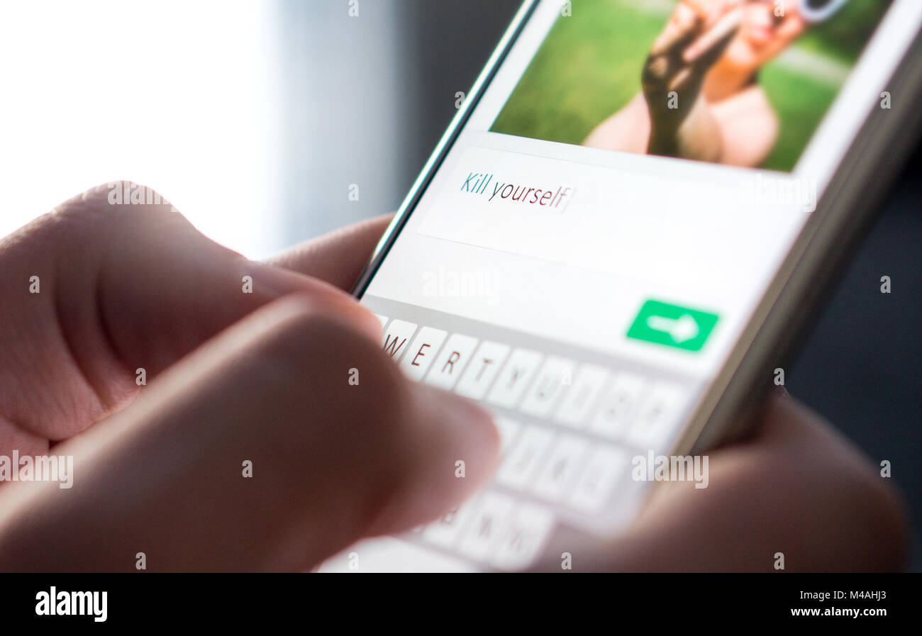 Cyber bullismo, internet trolling e cattivo comportamento on-line concept. Persona scrivendo significa 'kill te' commento all'immagine. Foto Stock