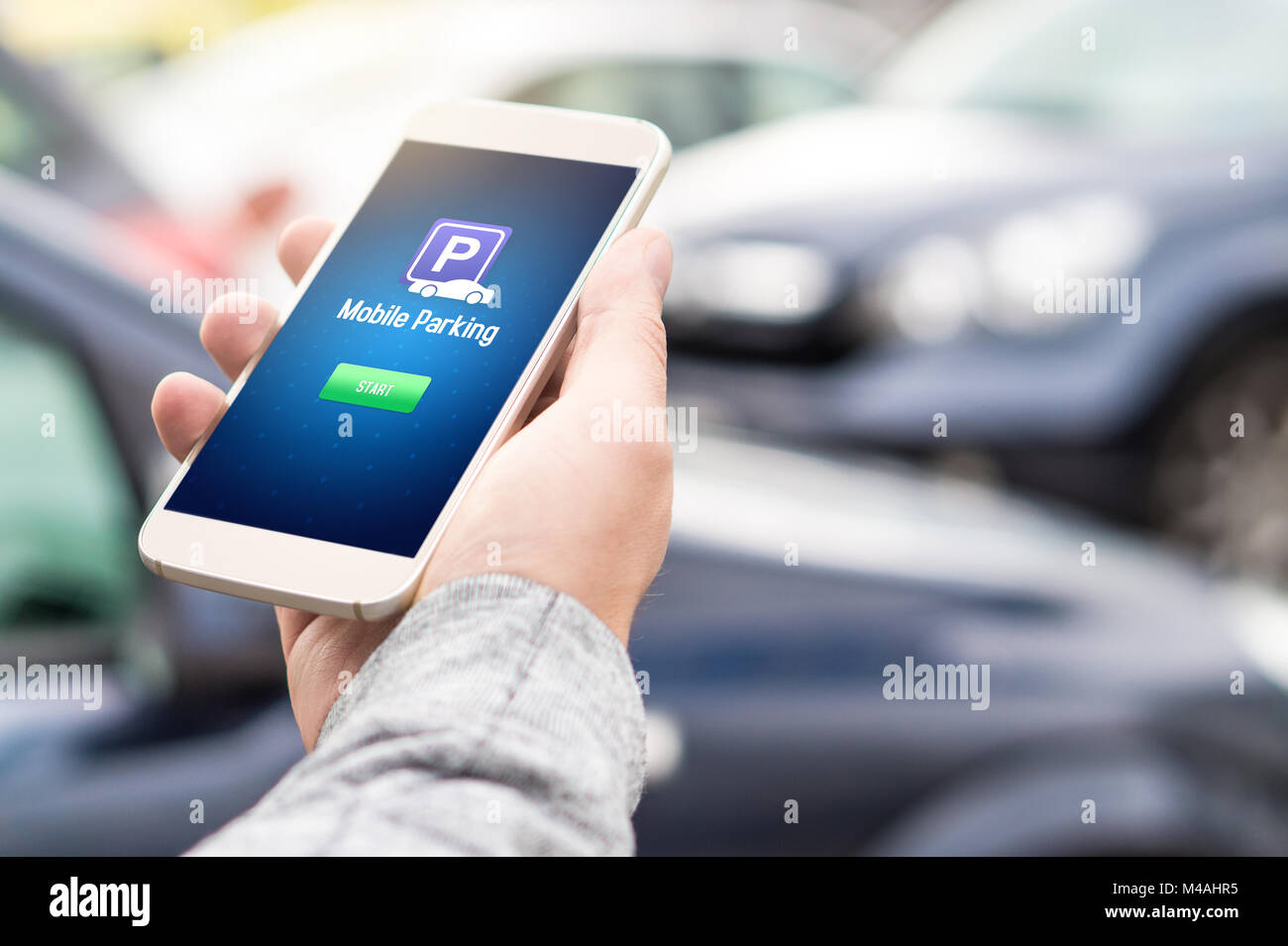 Parcheggio mobile app sulla schermata dello smartphone. Uomo con smart phone con parcheggio auto applicazione in mano. Internet il pagamento online con dispositivo moderno. Foto Stock