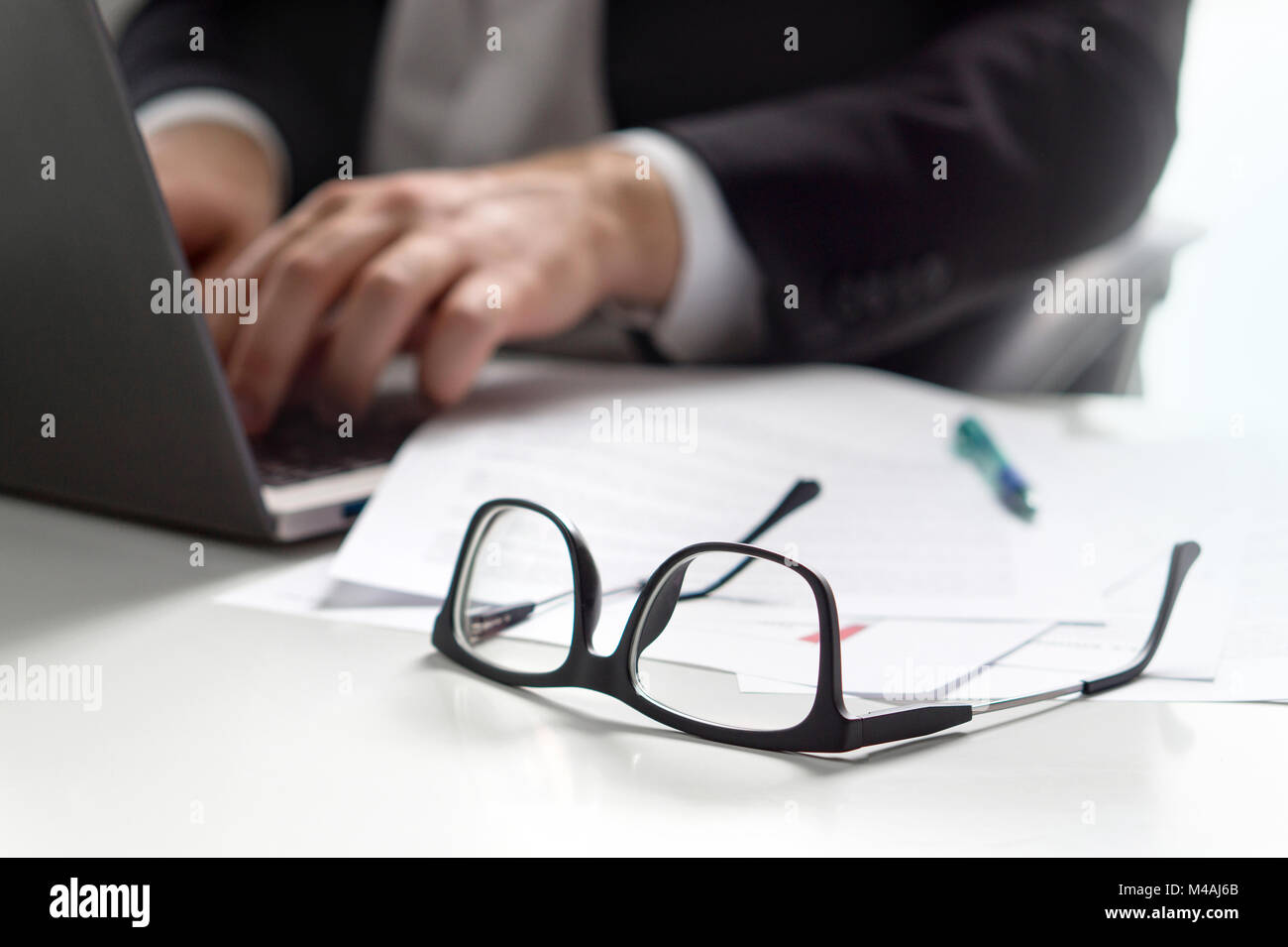 Business man la scrittura con il computer portatile in ufficio con bicchieri sul tavolo. Foto Stock