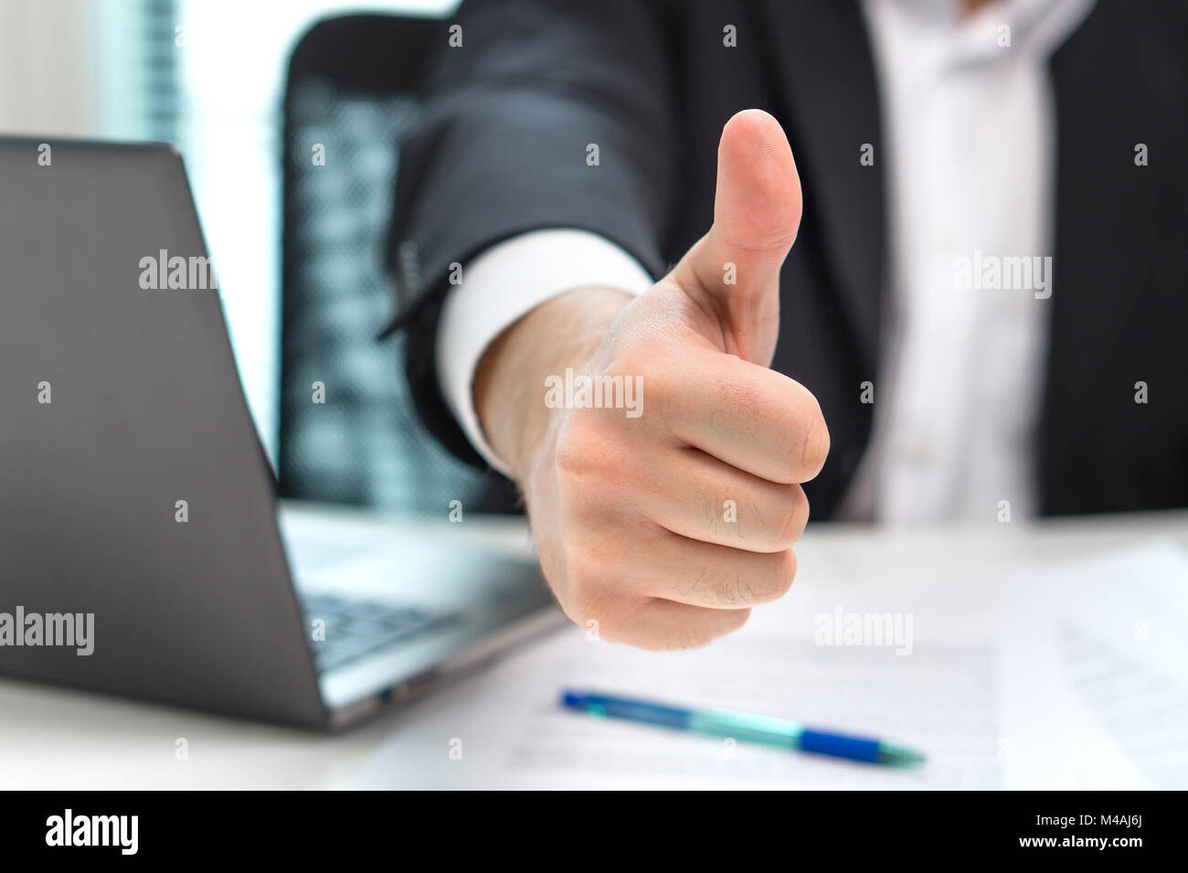 Uomo d'affari che mostra i pollici in su in ufficio. Foto Stock