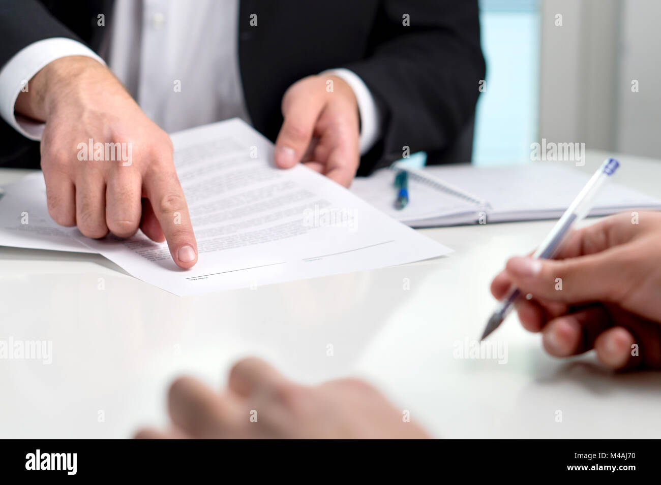 La firma di un contratto o accordo. Banchiere o un avvocato che mostra il client di linea per autografo in un documento cartaceo. Uomo d'affari con un cliente in ufficio. Foto Stock