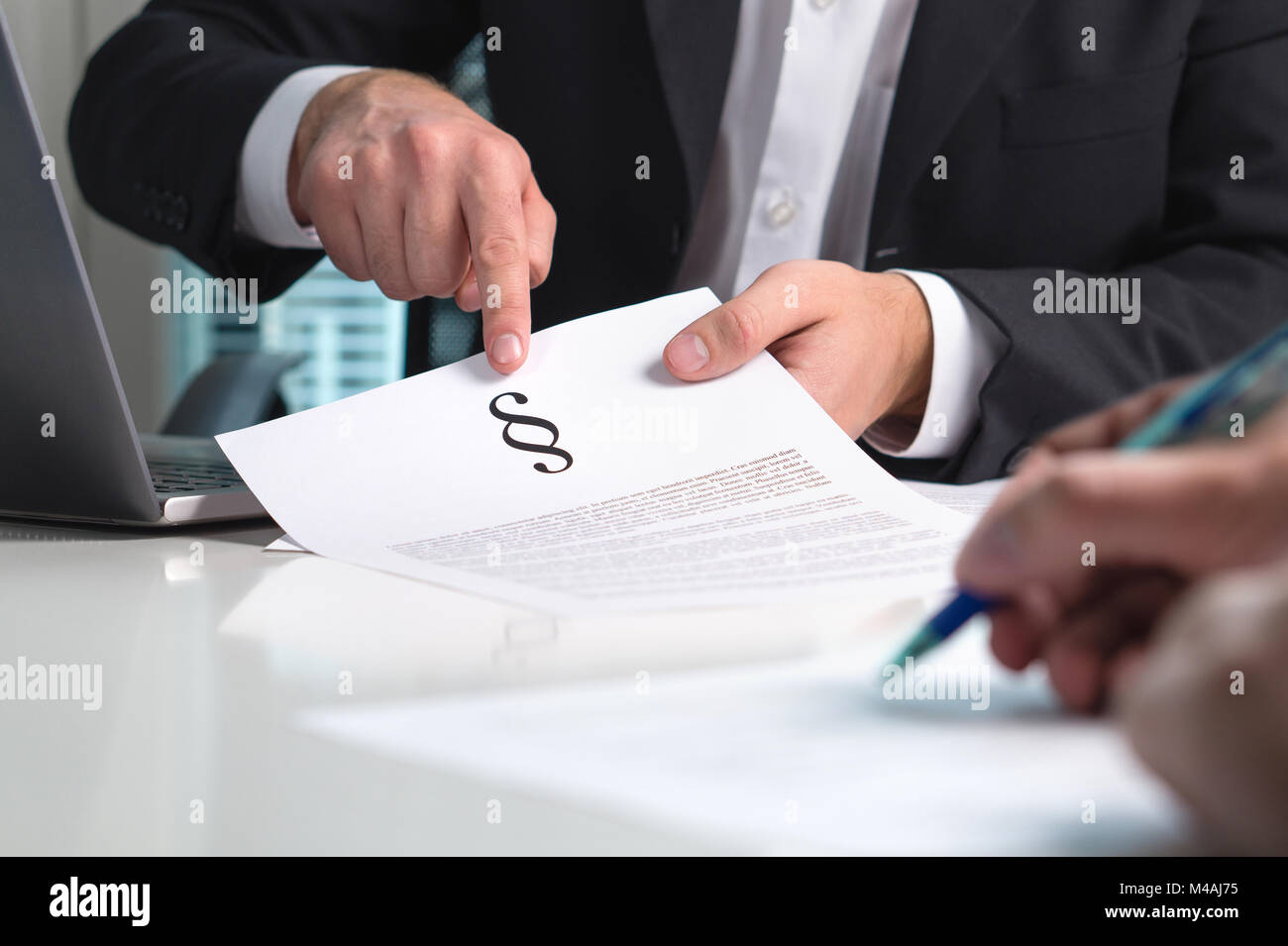 Avvocato fornendo consulenza legale per un client in ufficio. Persone in diritto impresa avente riunione. Attorney puntando una sezione segno su carta. Foto Stock