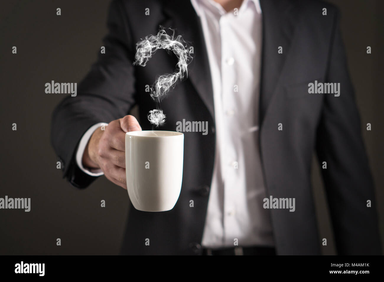 Punto interrogativo dal vapore di caffè. La formazione di fumo di un simbolo. Business man in una tuta in possesso di una bevanda calda in una tazza e tazza da tè. Foto Stock