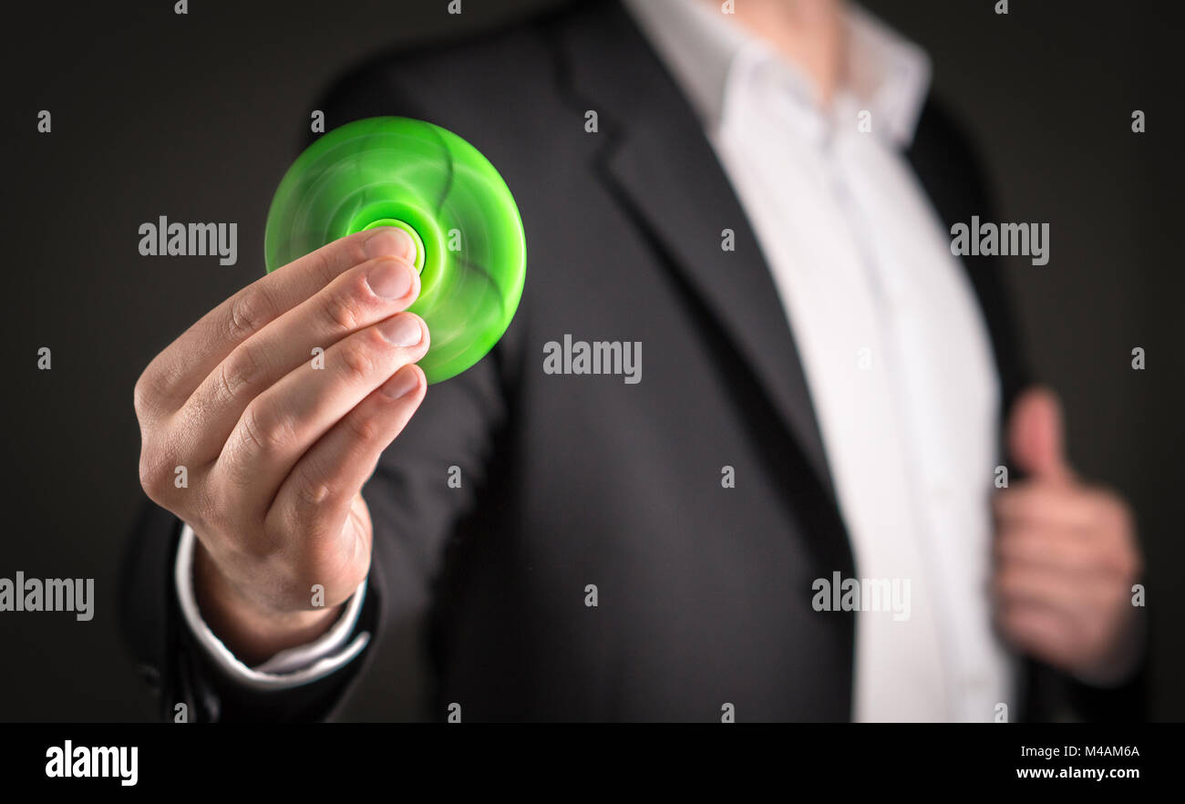 Uomo d'affari con un agitano: spinner. Imprenditore in posa di una tuta di contenimento per bambini alla moda ansia sollievo giocattolo in mano. Foto Stock