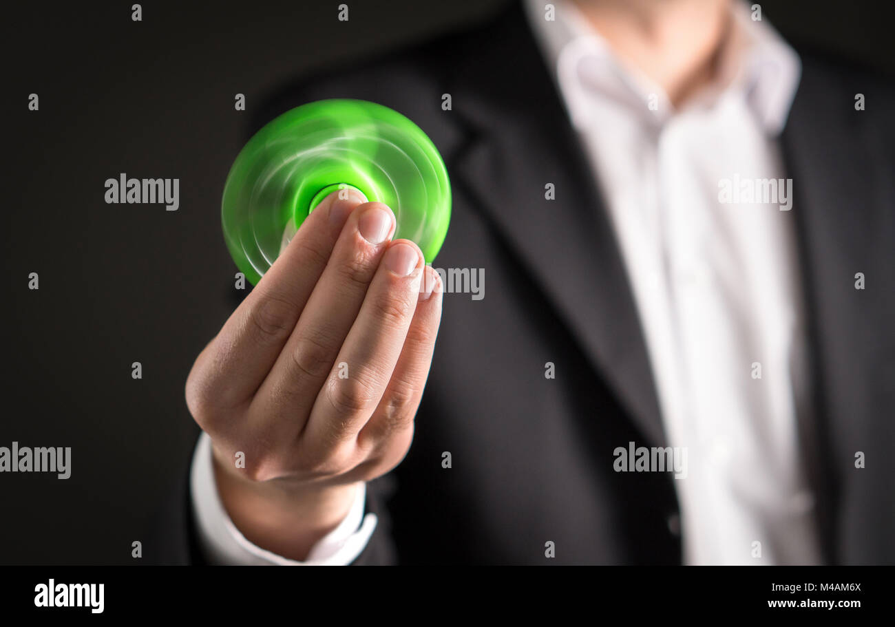 Uomo d'affari con un agitano: spinner. Imprenditore in un vestito tenendo trendy kids ansia sollievo giocattolo in mano. Foto Stock