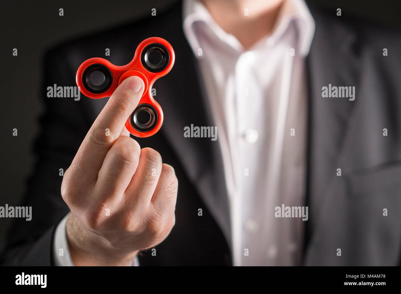 Uomo d'affari con un agitano: spinner. Imprenditore in un vestito tenendo trendy kids ansia sollievo giocattolo in mano. Foto Stock