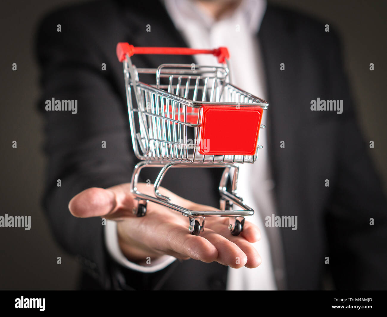 Negozio di alimentari a catena, di gestione e di vendita al dettaglio di beni di consumo quotidiano del concetto di commercio. Business man in un vestito con una piccola miniatura shopping cart. Foto Stock