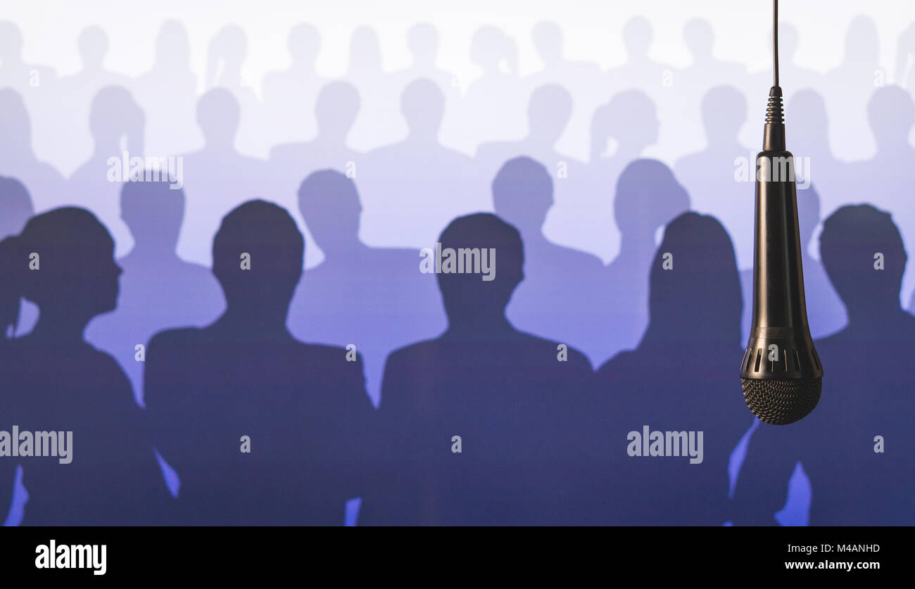 Parlare in pubblico e dare la parola. Il canto a microfono karaoke o talent show background. Microfono pendenti dal soffitto dal filo di fronte ad una folla. Foto Stock