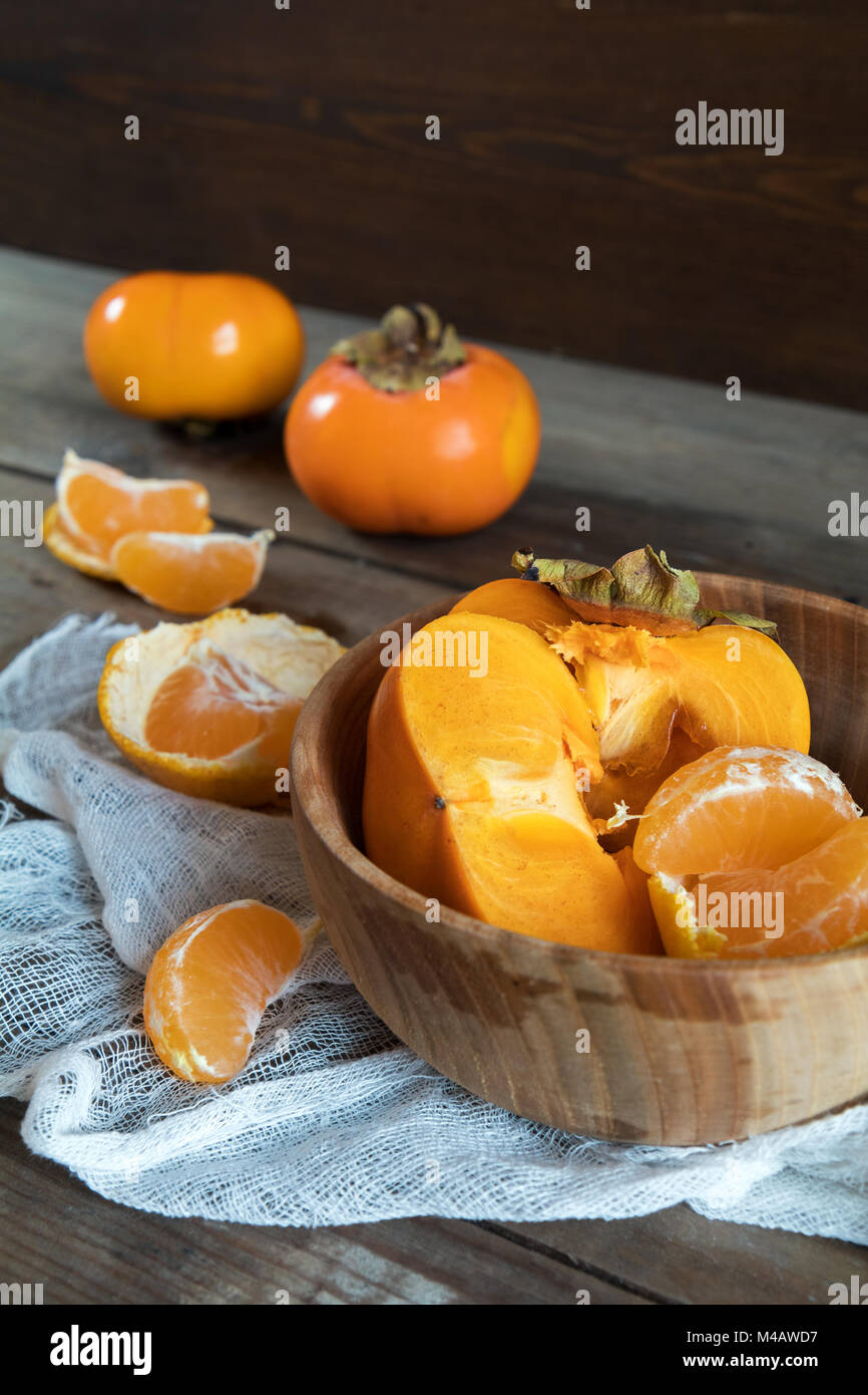 Fresche cachi e mandarini frutti nel recipiente Foto Stock