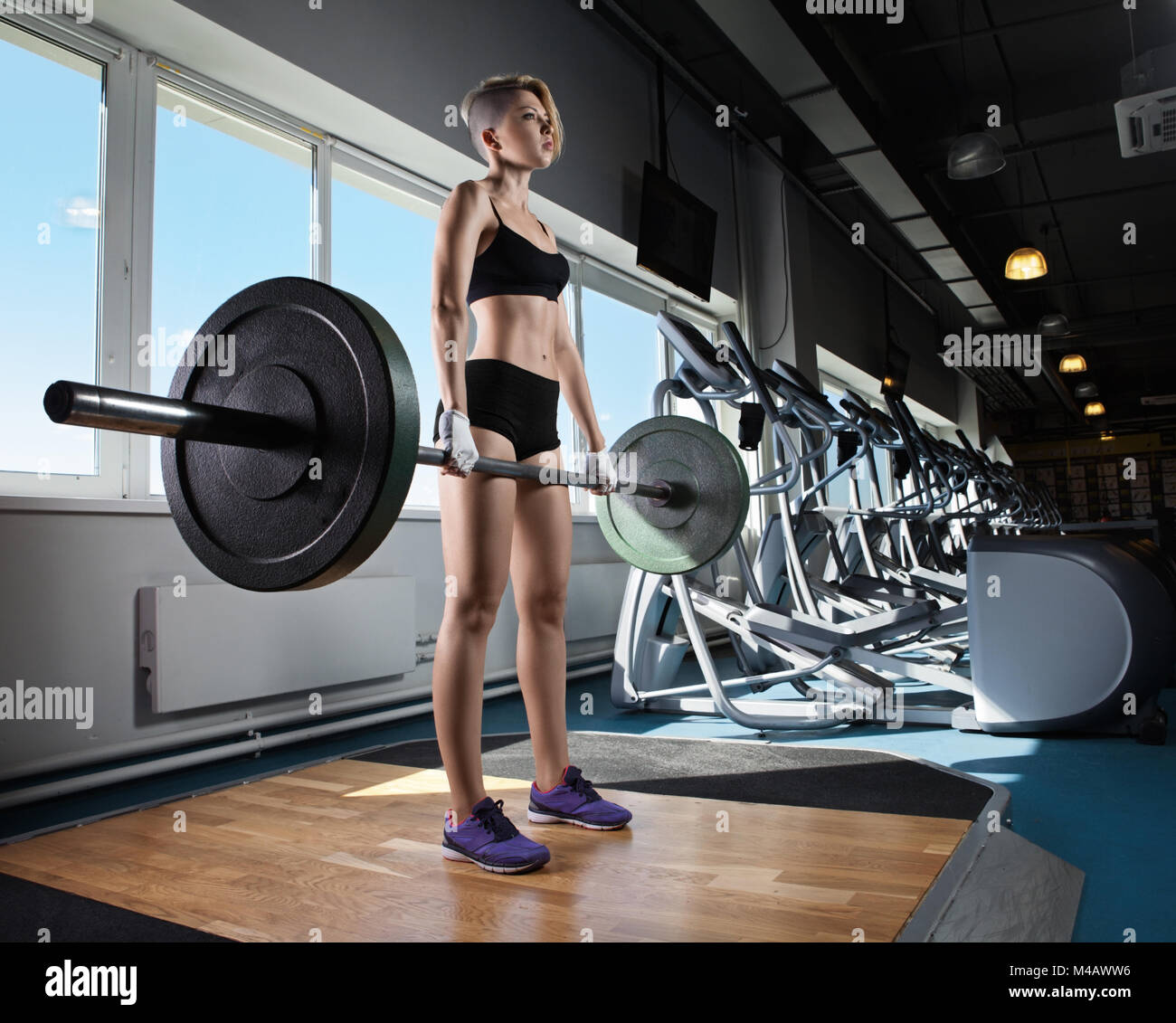 Donna muscolare in una palestra facendo pesanti esercizi di peso Foto Stock