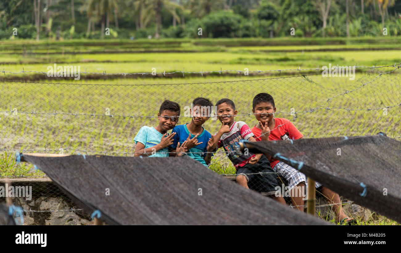 Quattro bambini balinese giocare in campi di riso di Bali, Indonesia Foto Stock