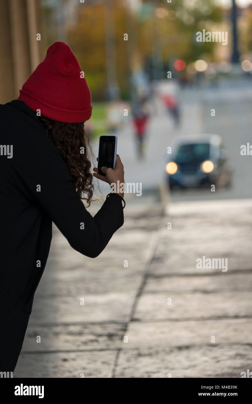 Ragazza con maglia di Red Hat e un telefono mobile,di scattare le foto, Foto Stock