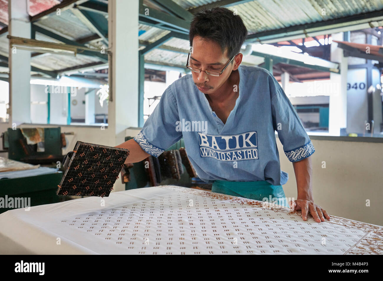 Il produttore di batik stampa la cera calda su un panno con un timbro di rame. Negozio Batik Winotosastro, Yogyakarta, Giava, Indonesia. Foto Stock