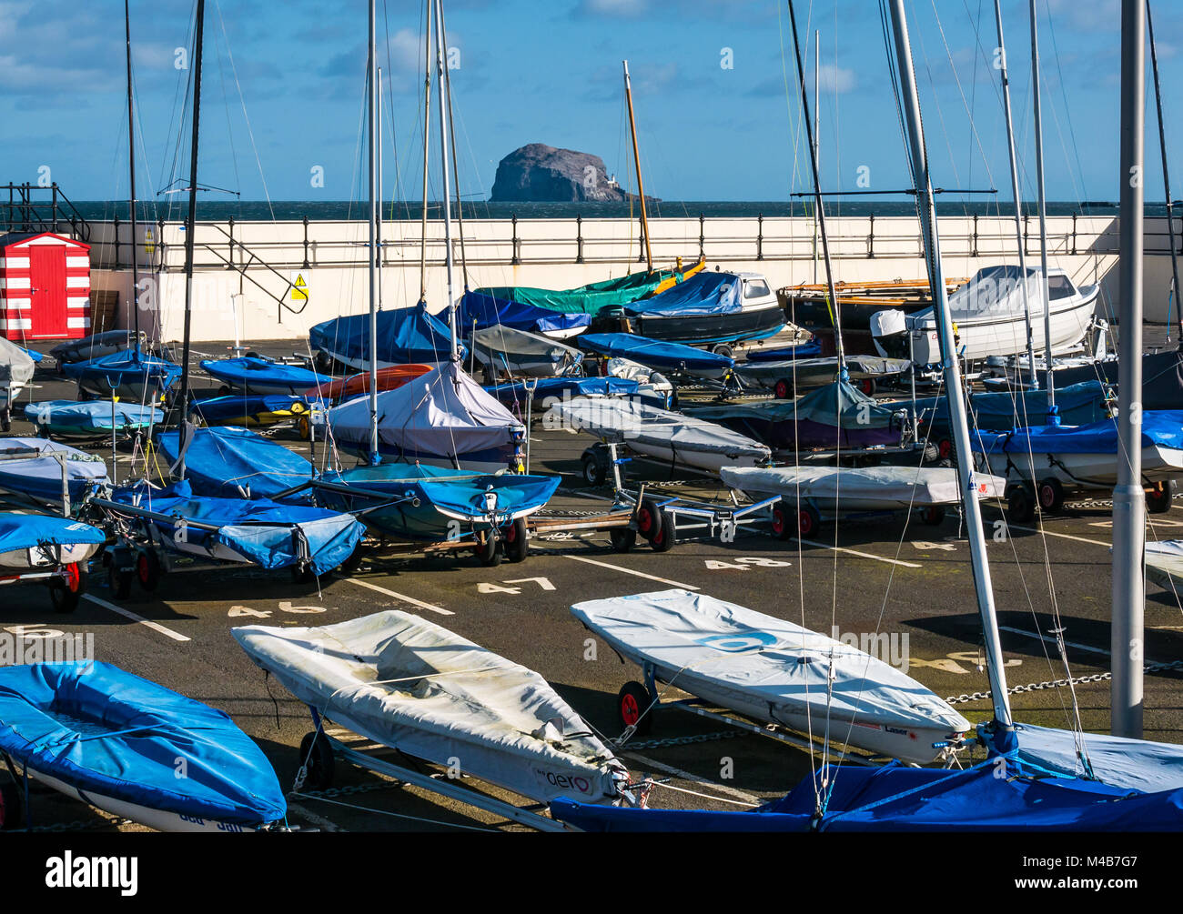 A North Berwick Yacht Club coperto barche nel porto con piloni, Bass Rock e faro sull orizzonte, Scotland, Regno Unito Foto Stock