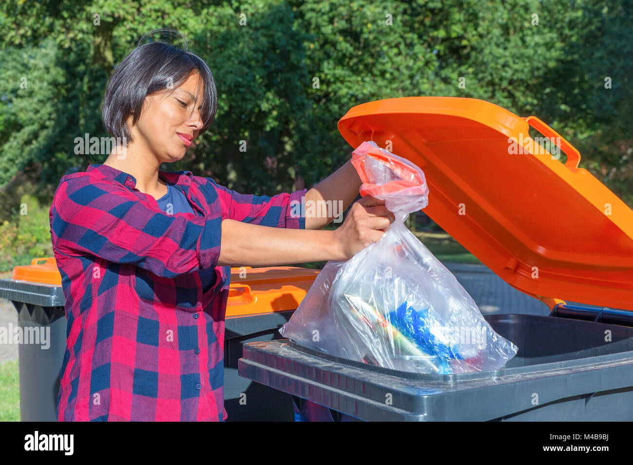 Donna olandese buttare immondizia di plastica in thrash bin Foto Stock