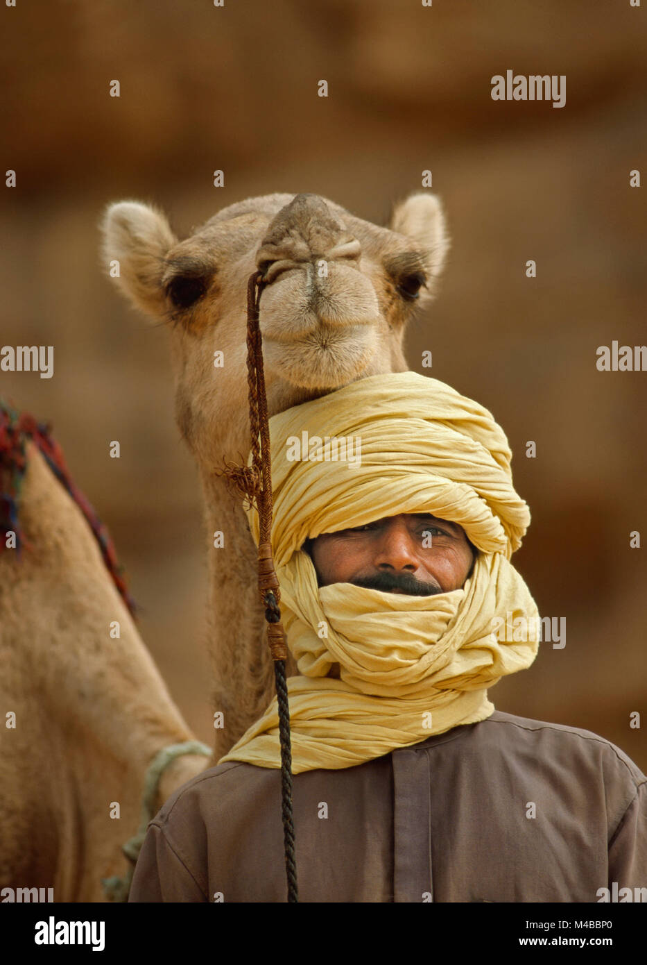 Algeria, Djanet. Uomo di tribù Tuareg e cammello. Deserto del Sahara. Ritratto. Foto Stock