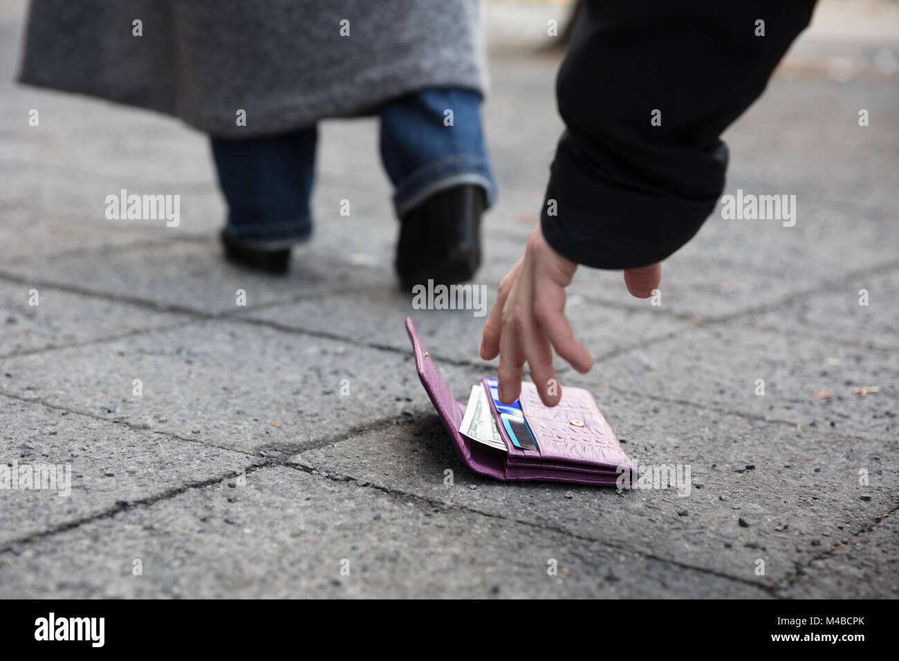 In prossimità di un uomo di prelevare un portamonete perduto sulla strada Foto Stock