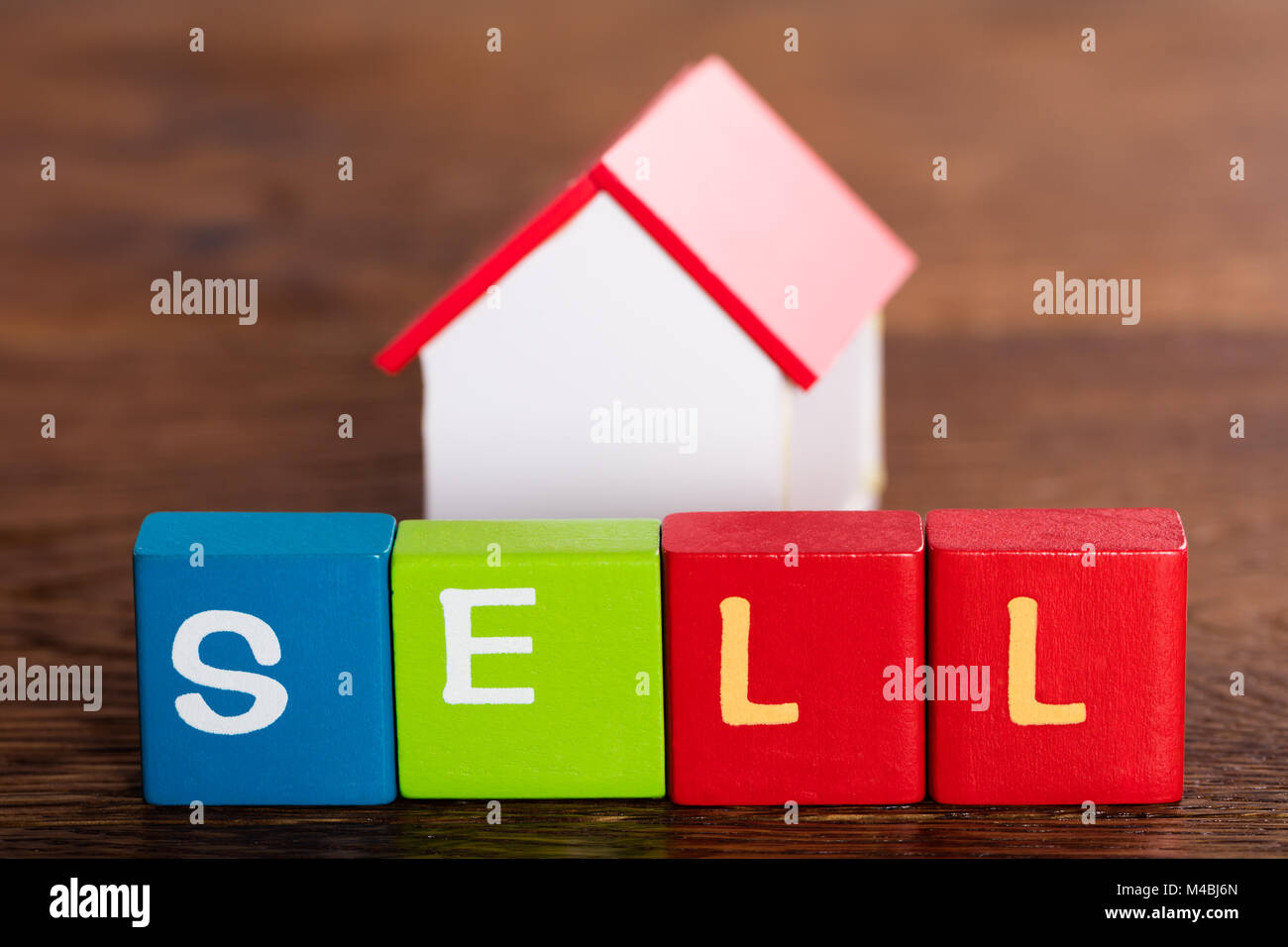 Modello di casa dietro la parola vendere su più blocchi colorati Foto Stock